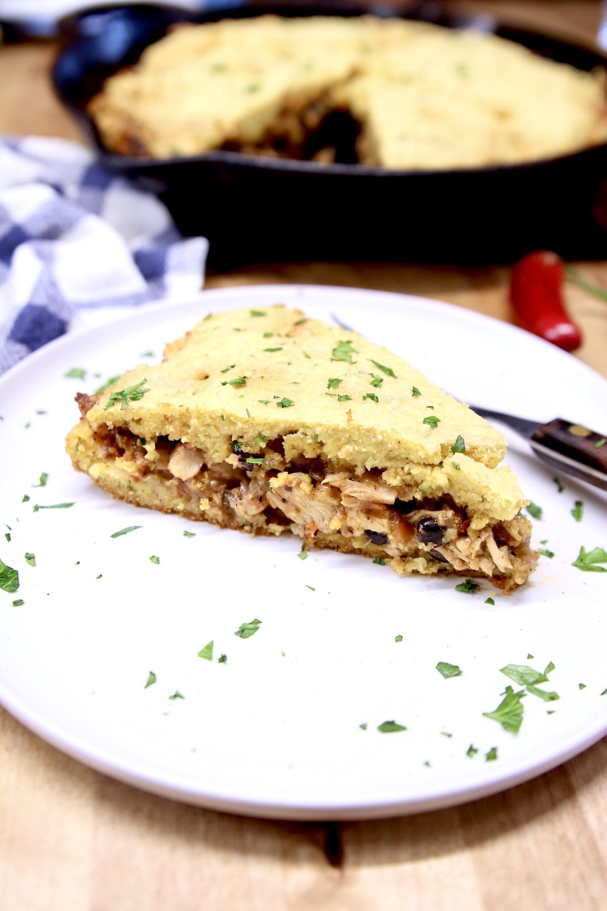 slice of Mexican Chicken Cornbread on a saucer - skillet in background