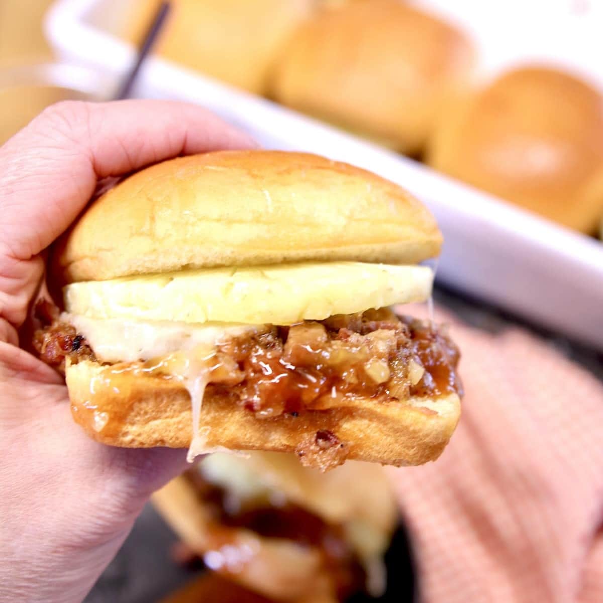 Pineapple pulled pork slider held in hand.