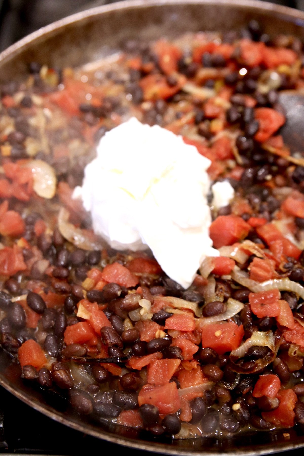 black beans and tomatoes with sour cream in a skillet