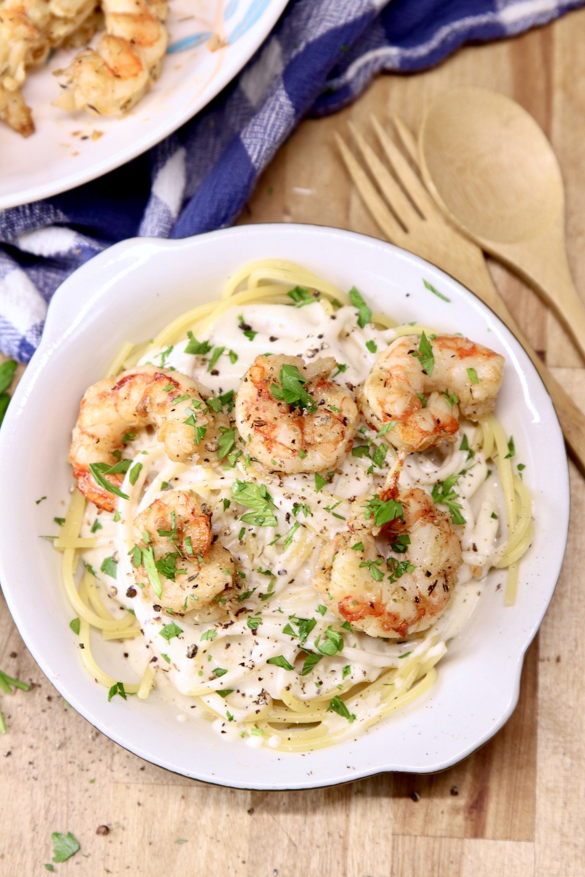 Creamy Shrimp Pasta is super quick and easy for busy weeknights. A tangy cream sauce tossed with spaghetti and topped with garlic butter shrimp is a tasty meal that is sure to become a family favorite. Creamy Shrimp Pasta in a bowl