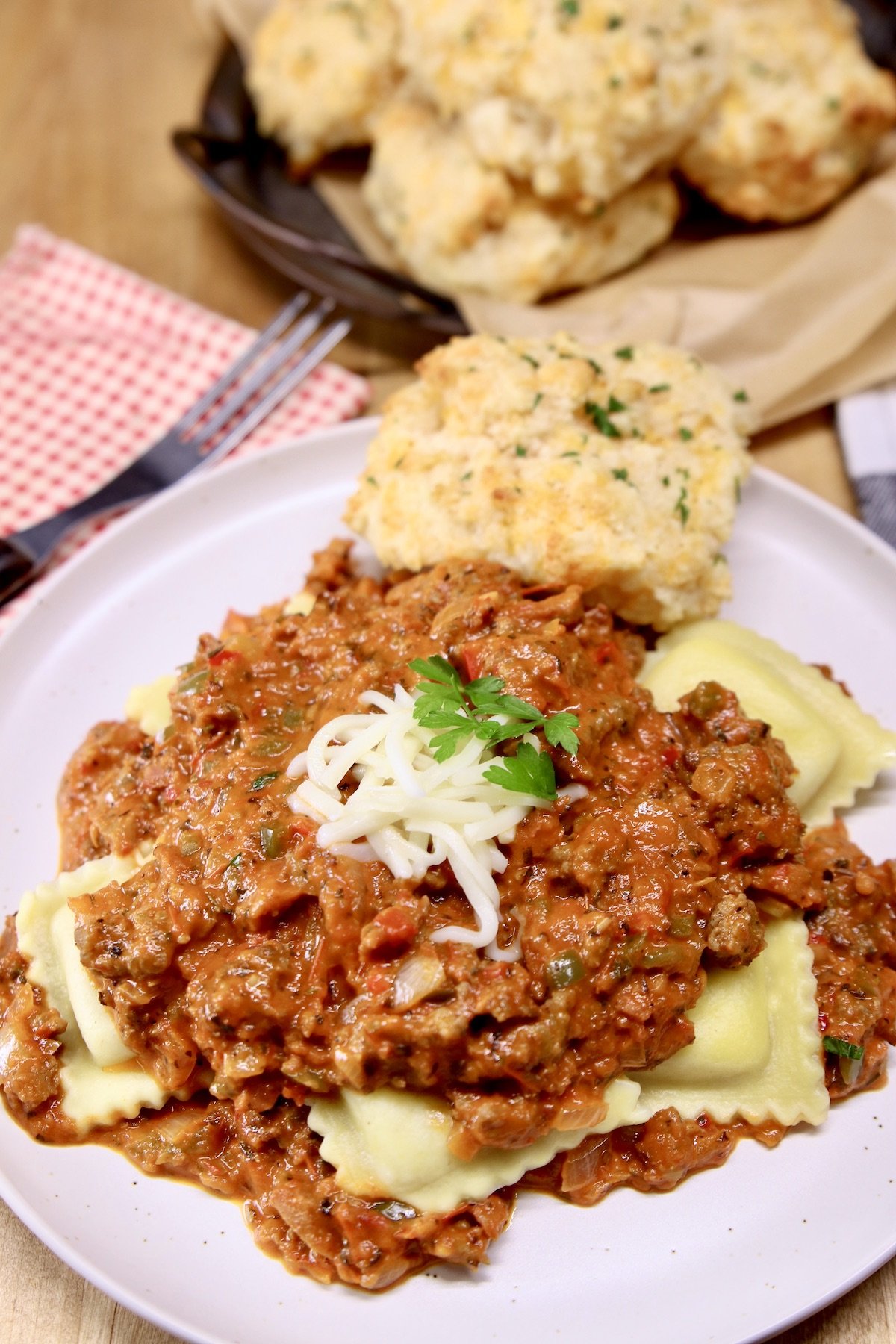Ravioli with meat sauce on a plate with a garlic cheese biscuit
