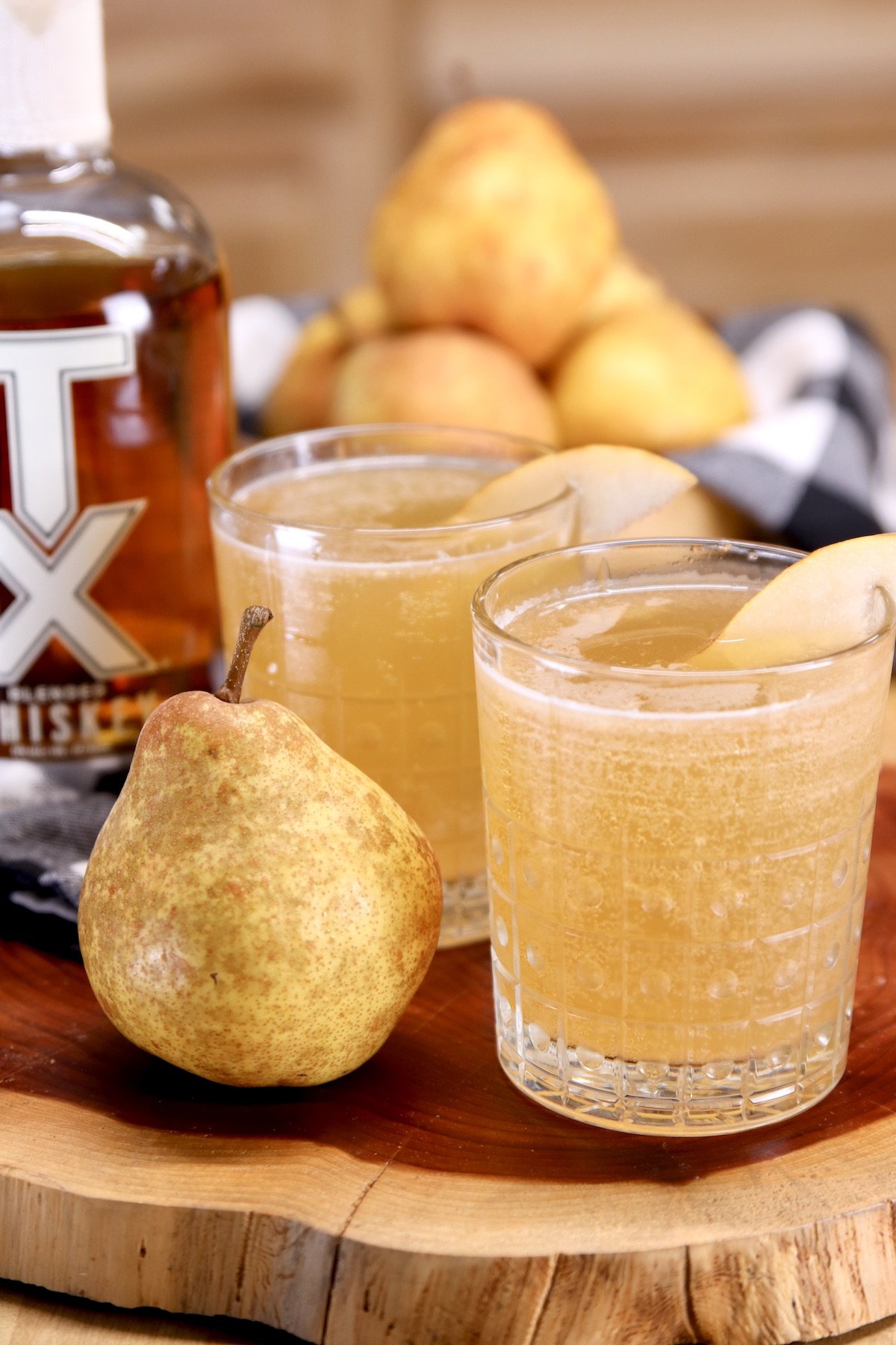 2 pear cocktails with TX Whiskey, whole pear on a live edge board