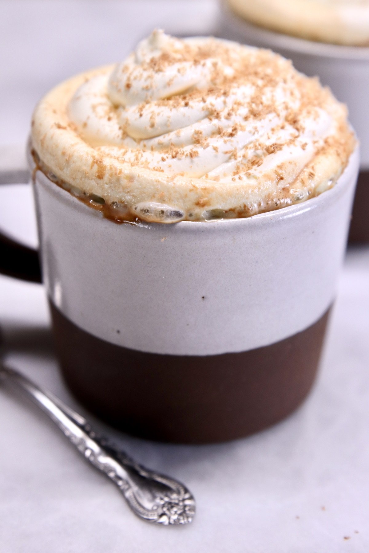 Mug of raspberry hot chocolate with whipped cream and shaved chocolate in a mug