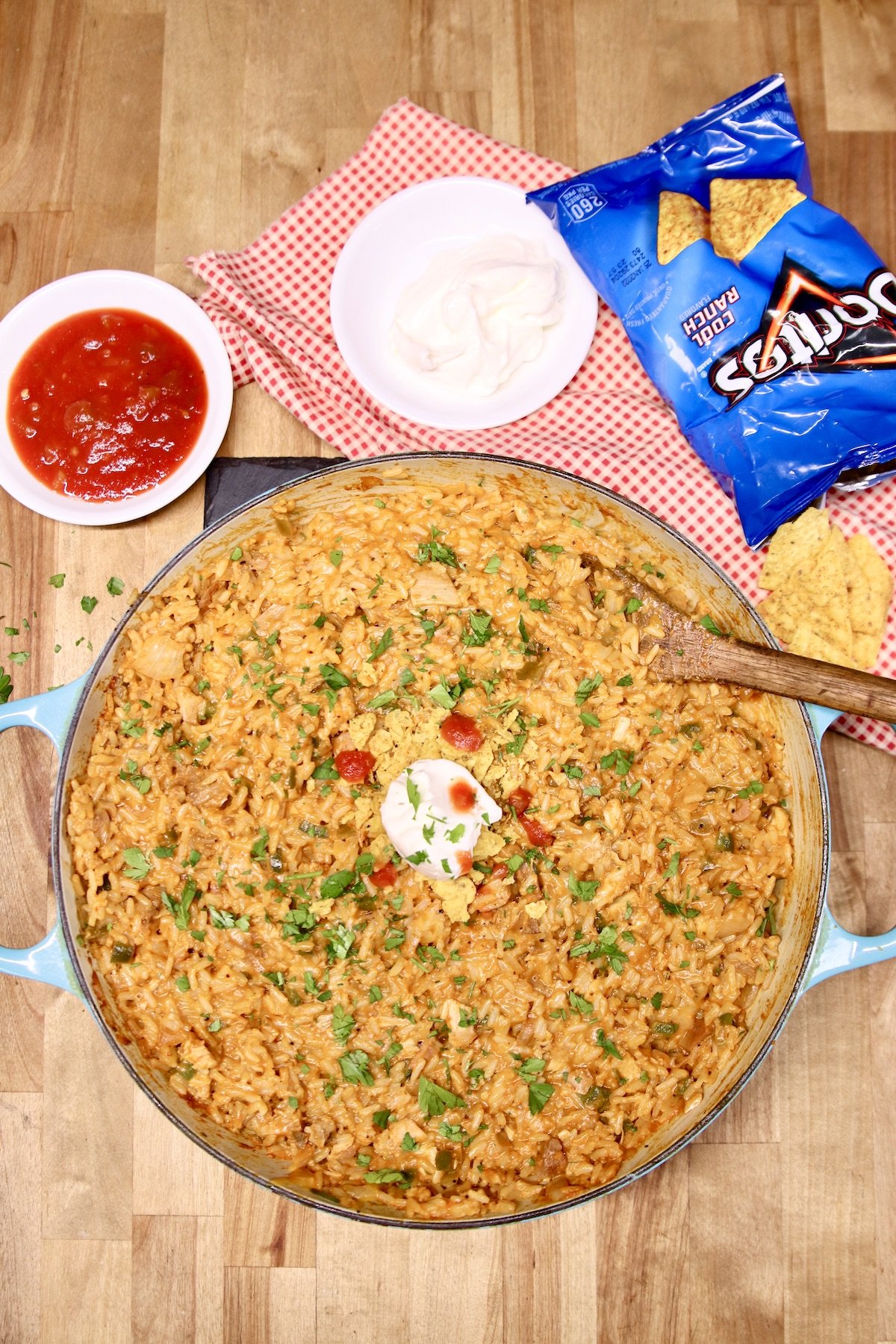 cheesy chicken taco rice in a pan, salsa, sour cream, doritos