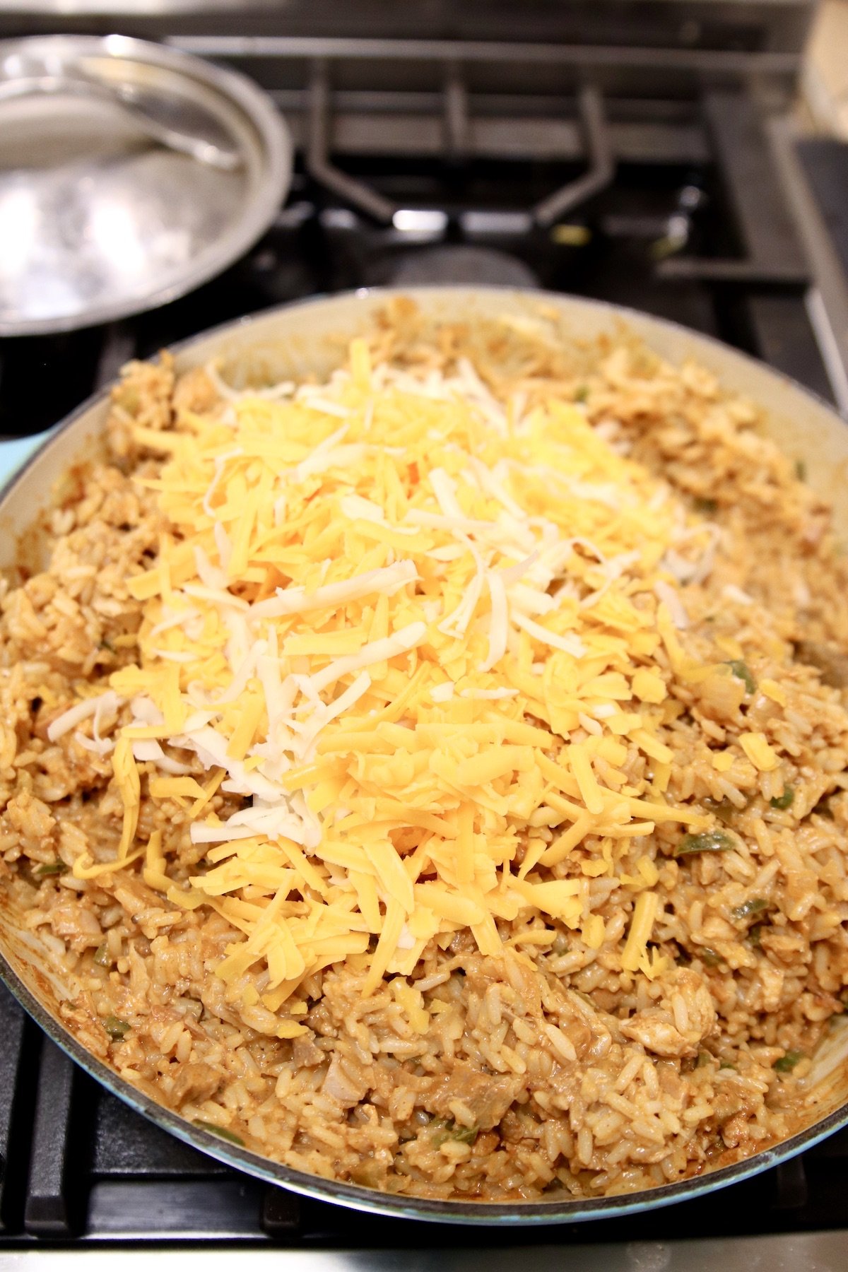 adding cheese to a skillet of chicken and rice