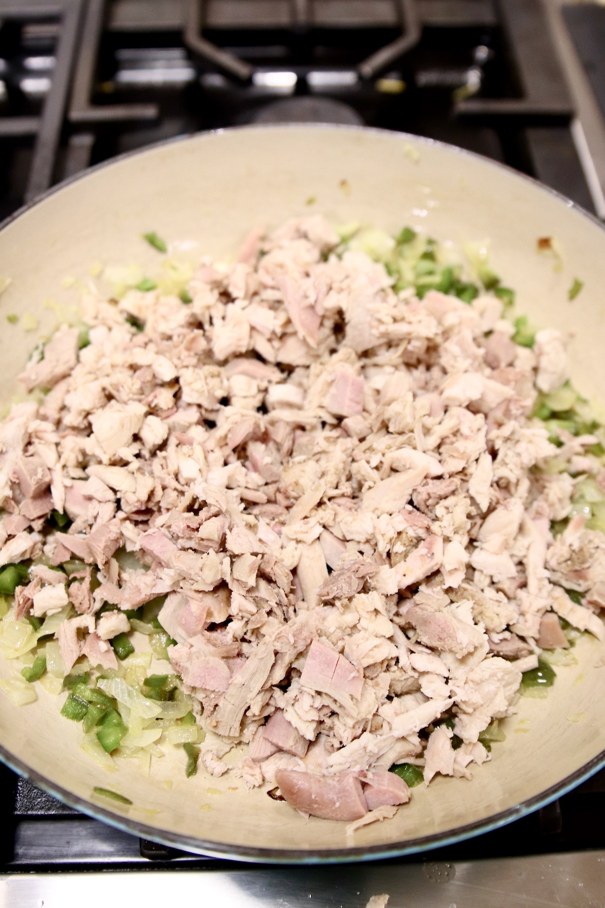 chopped chicken in pan with peppers and onions
