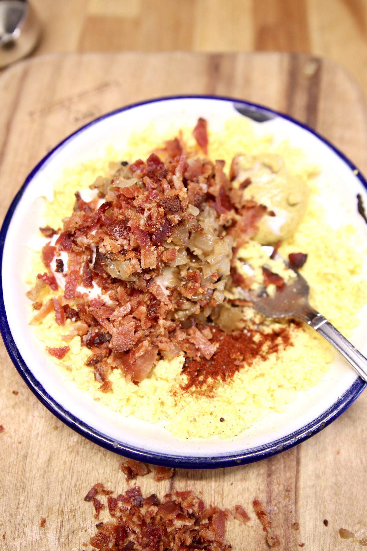 egg yolks in a bowl with bacon, onions for deviled eggs