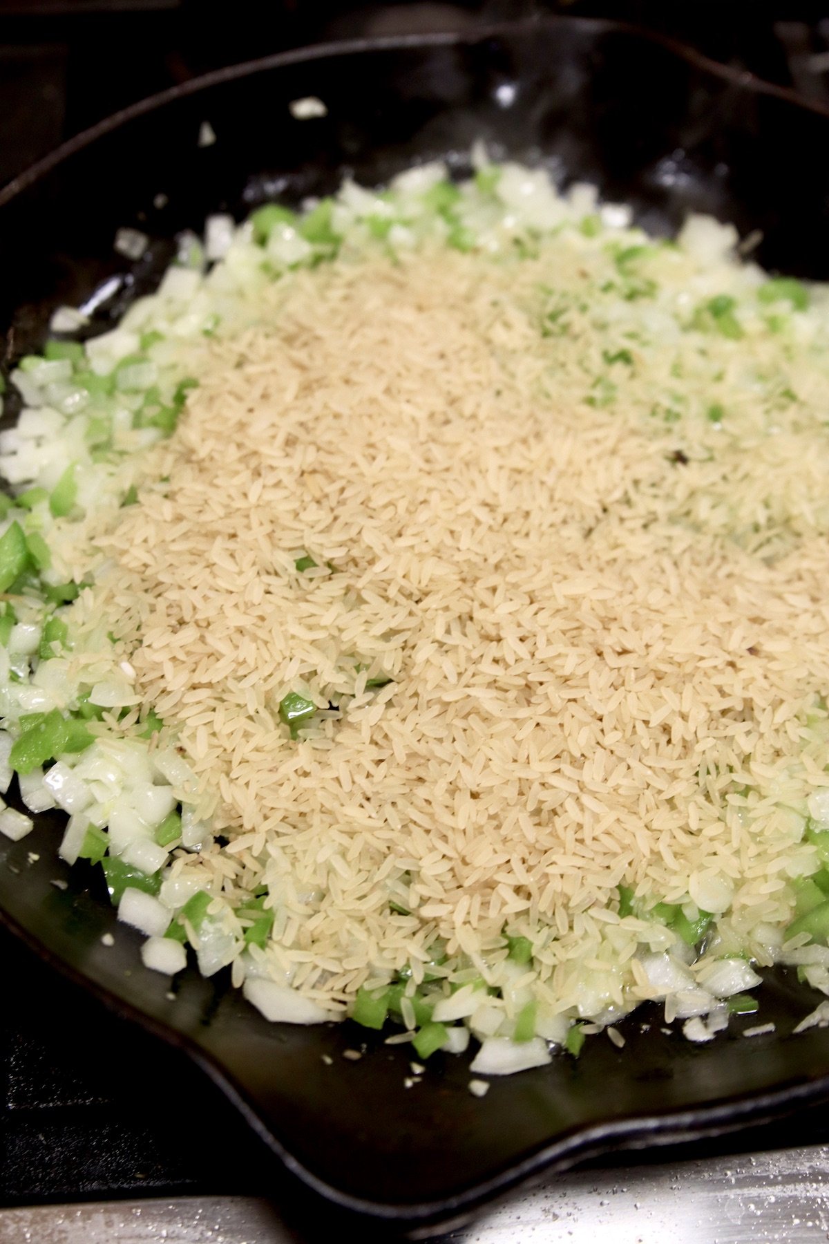 Skillet with cooked onions, bell peppers with rice
