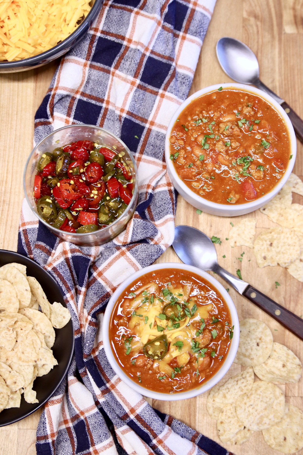 venison chili in 2 bowls with cheese, jalapenos and tortilla chips