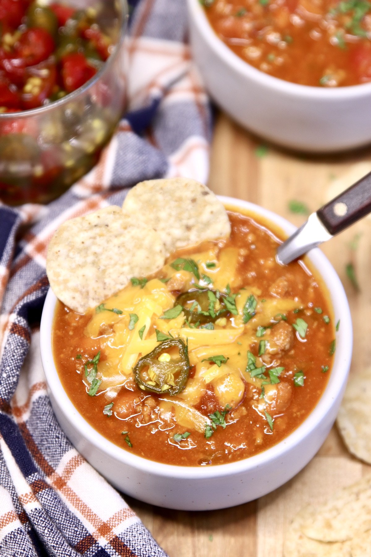 bowl of chili topped with cheese, tortilla chips