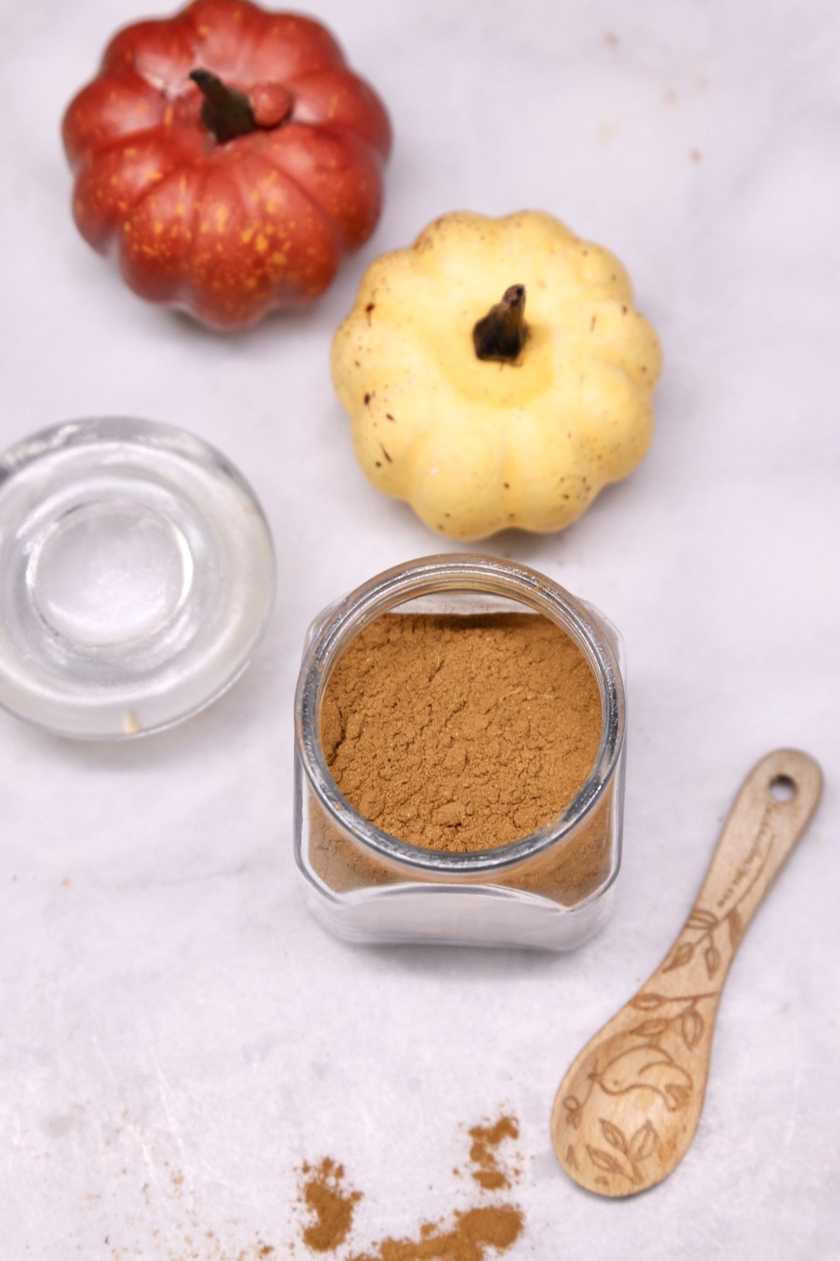 overhead view of pumpkin pie spice in a jar, 2 small decorative pumpkins