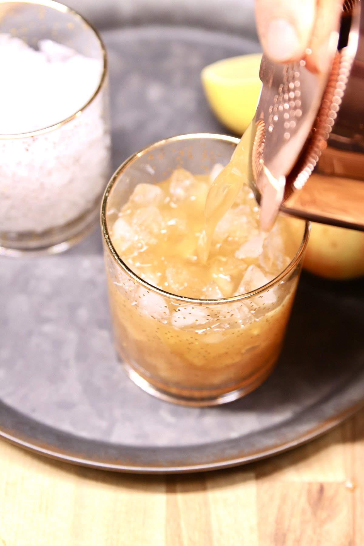 pouring cocktail into a rocks glass over ice