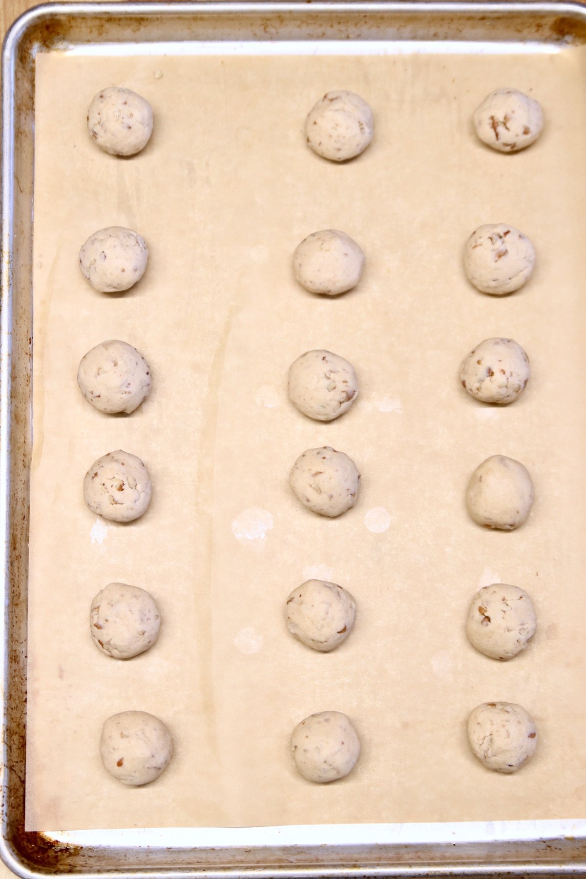 baked snowball cookies on parchment lined baking sheet