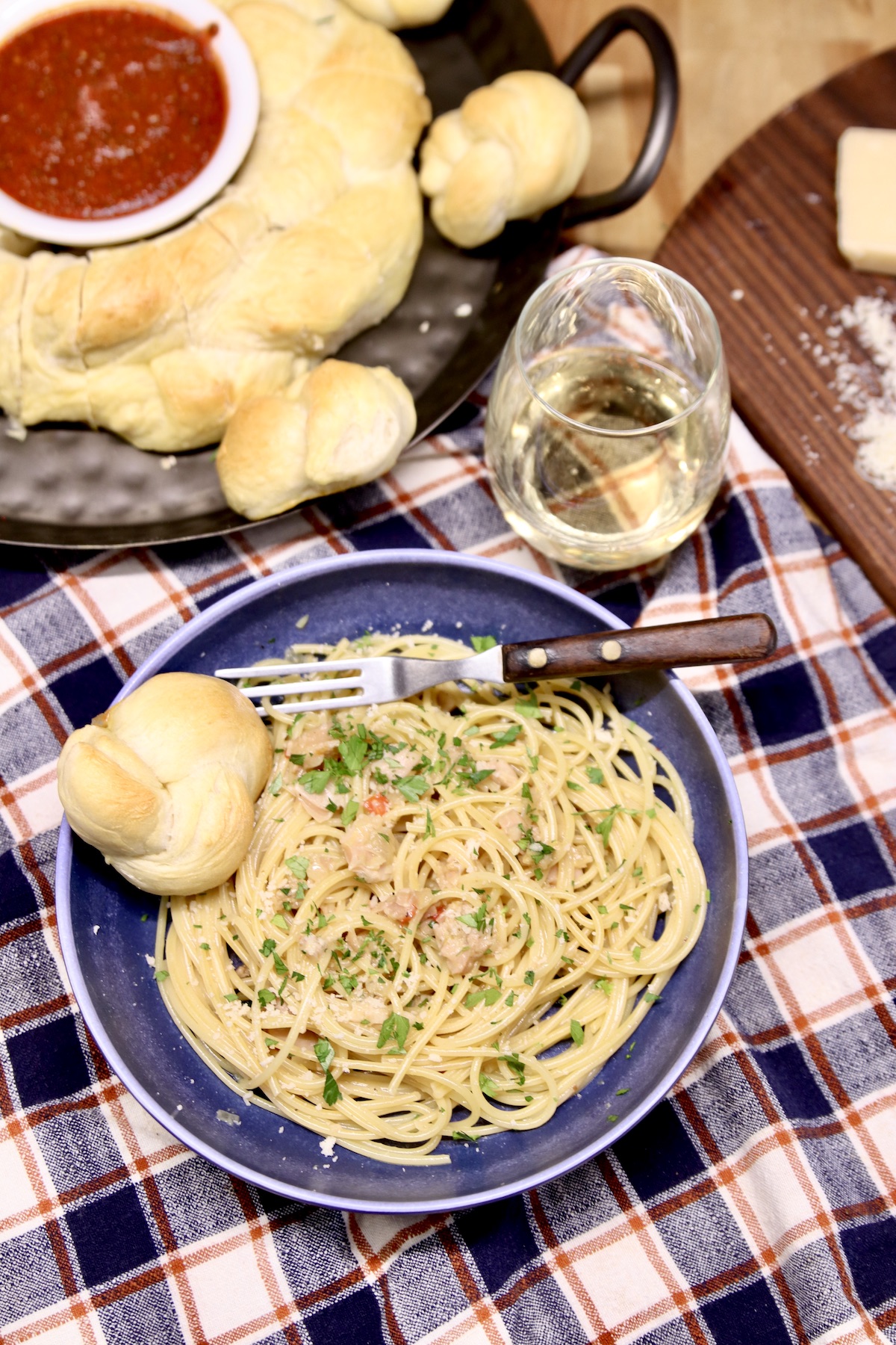 bowl of pasta with clam sauce -bread in back ground