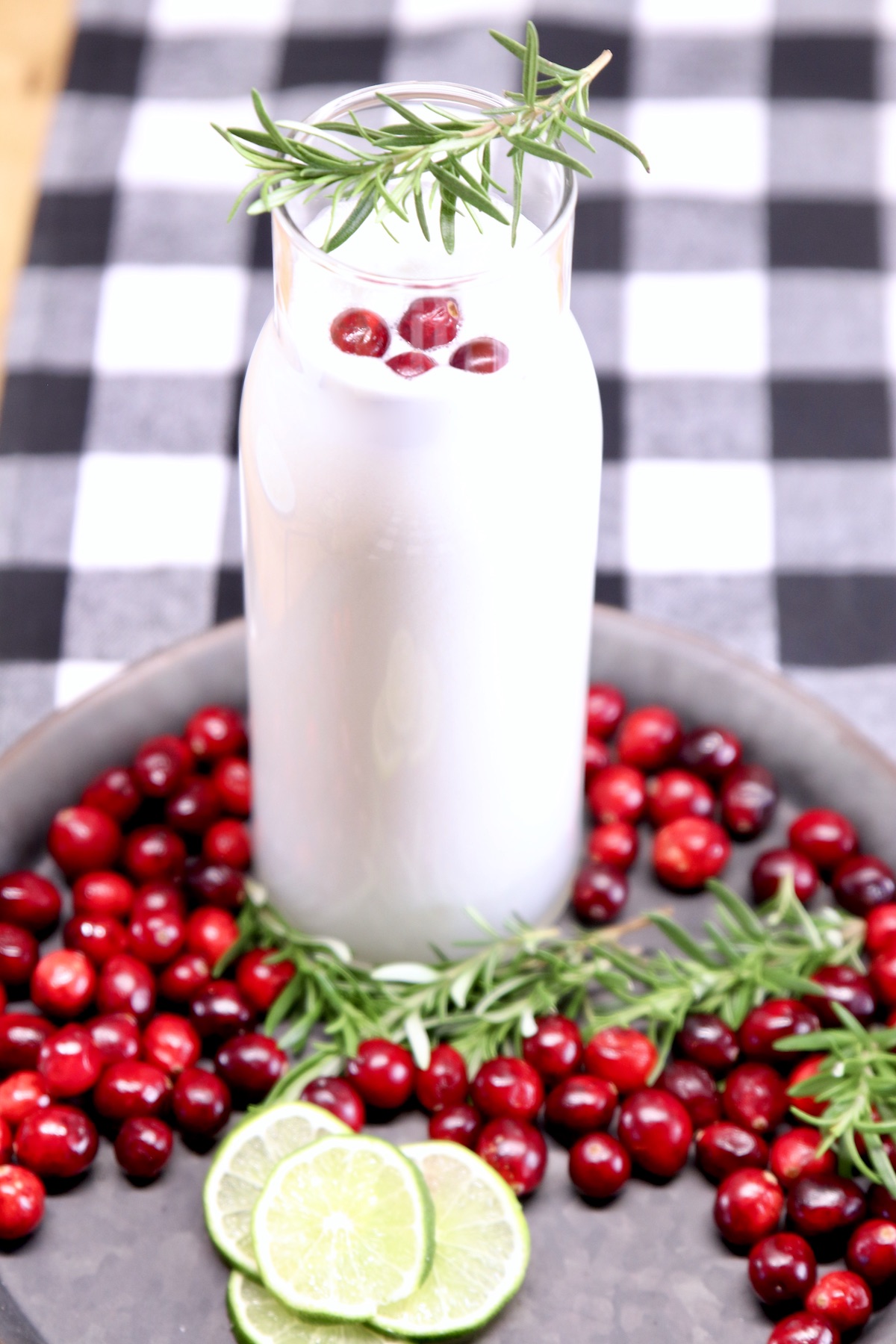 pitcher of white Christmas margaritas with cranberry garnish on a tray