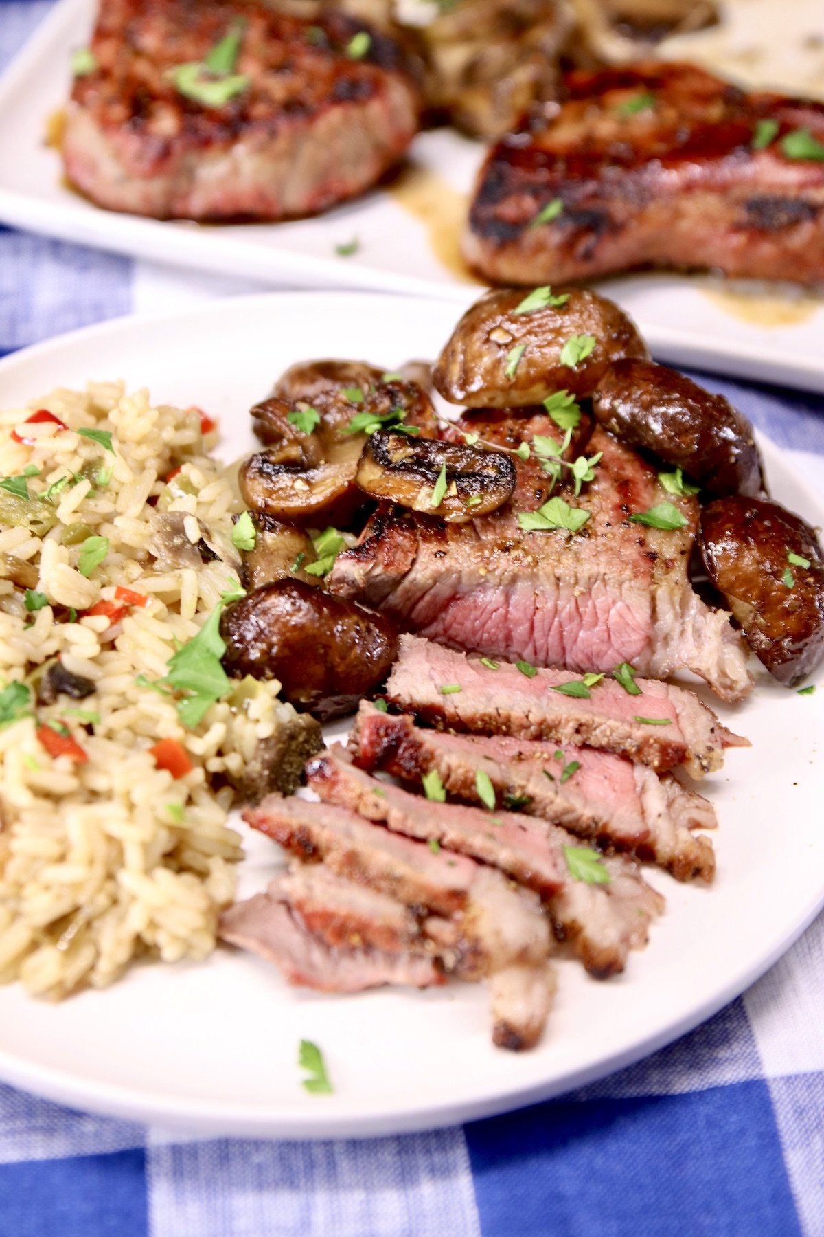 grilled steak sliced on a plate with rice and mushrooms