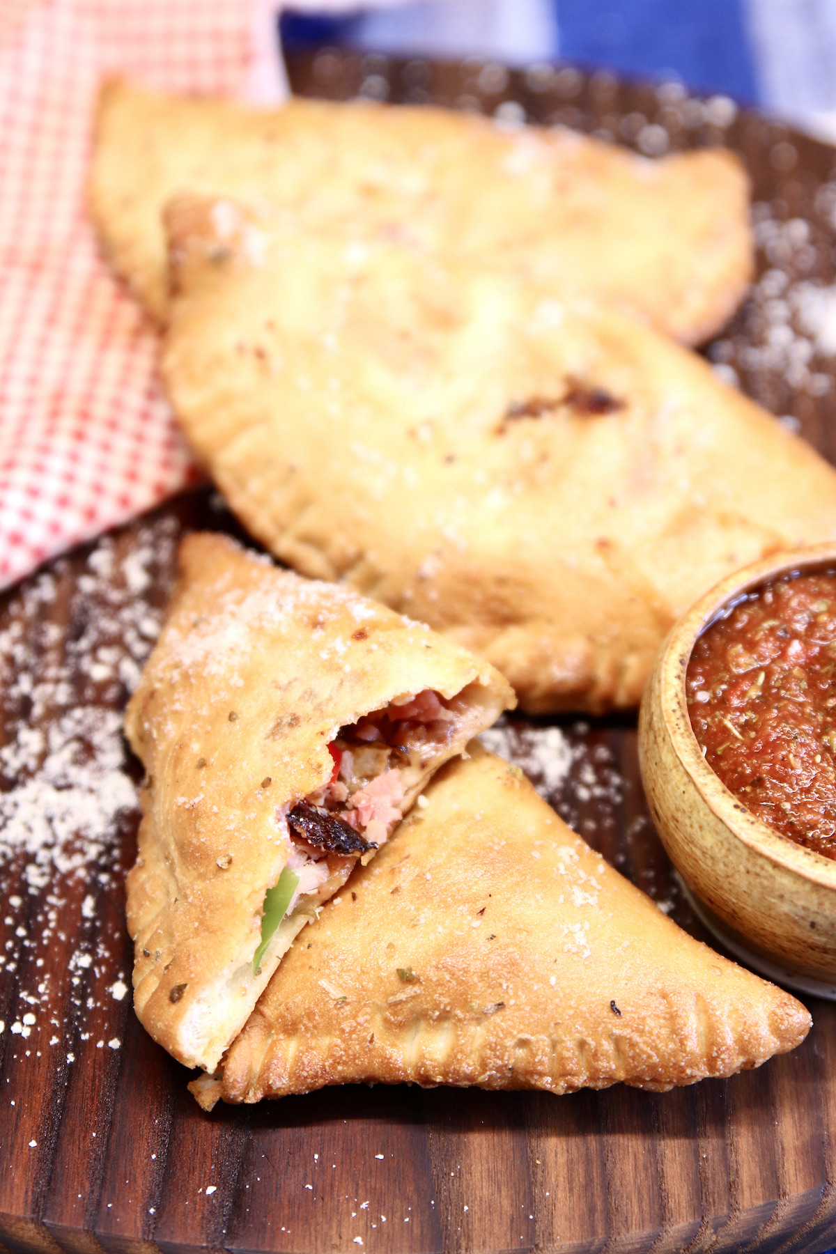 air fryer calzones - 3 on a cutting board with pizza sauce
