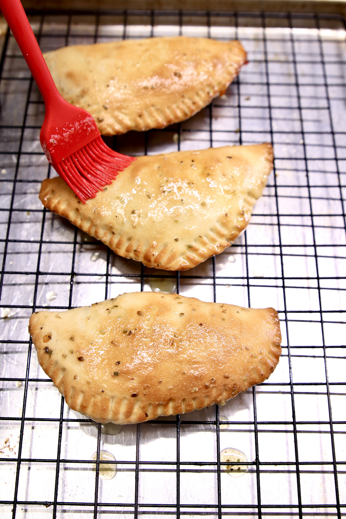 brushing garlic butter over calzones