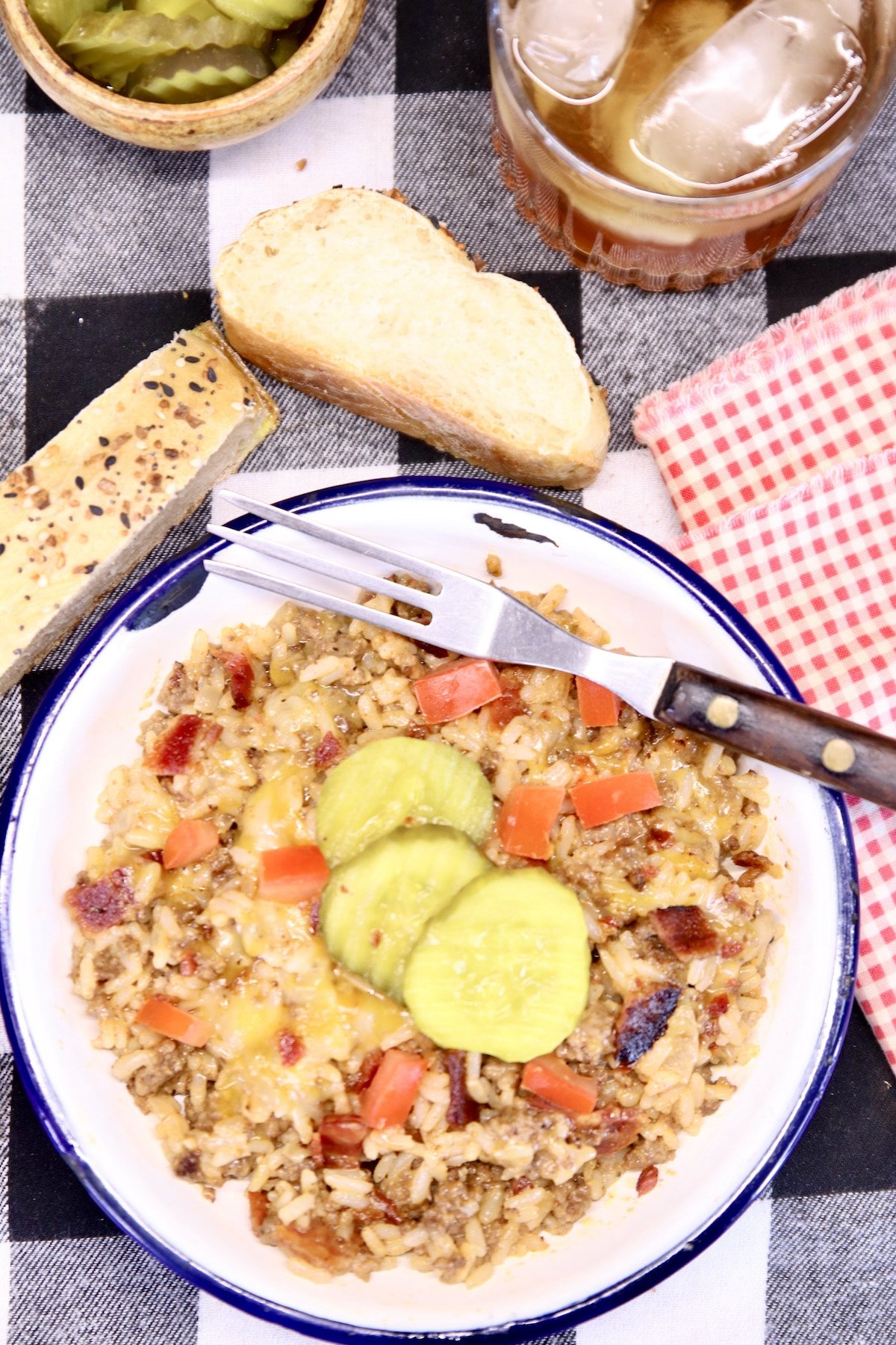bacon cheeseburger rice in a bowl with chopped tomatoes and sliced pickles