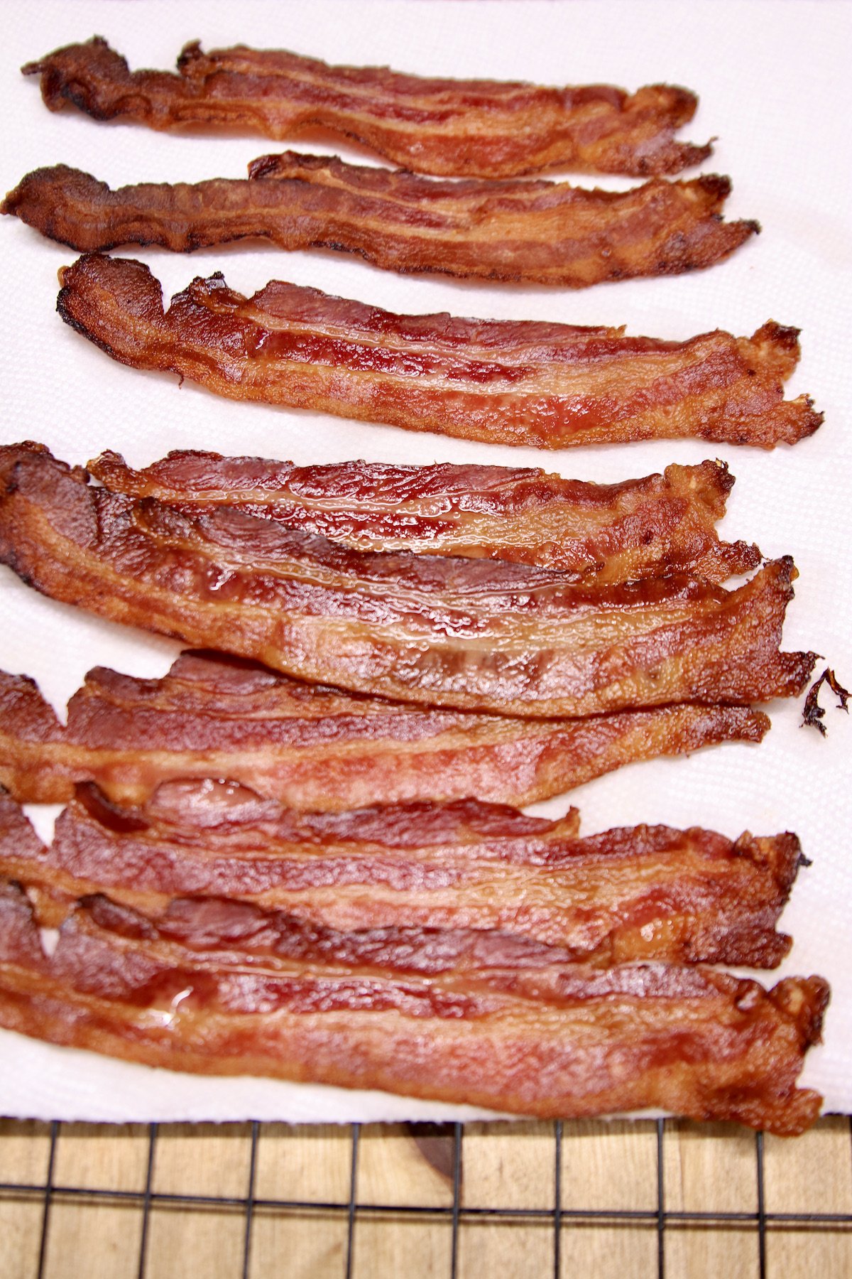cooked bacon strips on a wire rack with paper towel.