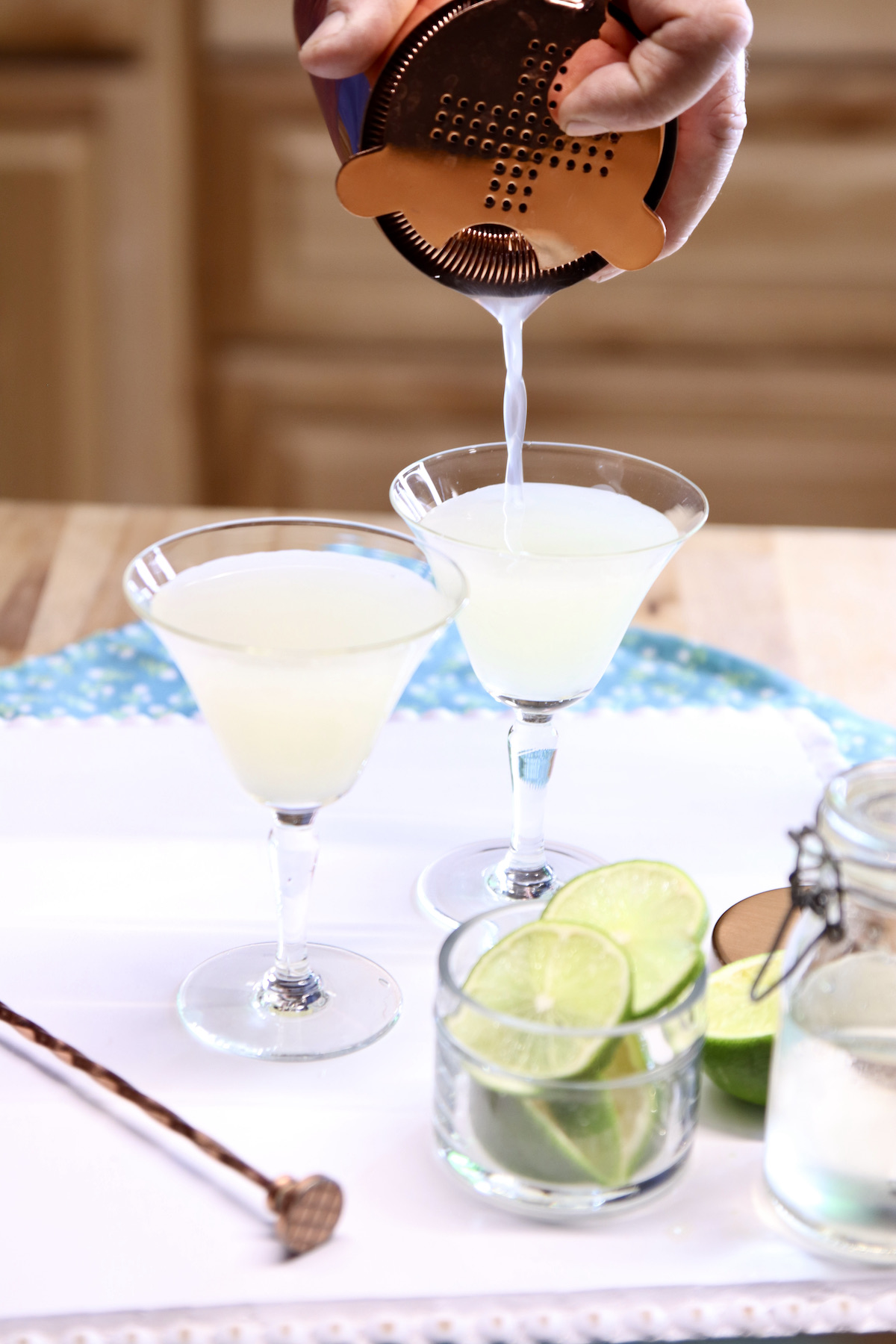 straining gimlet cocktail into glasses