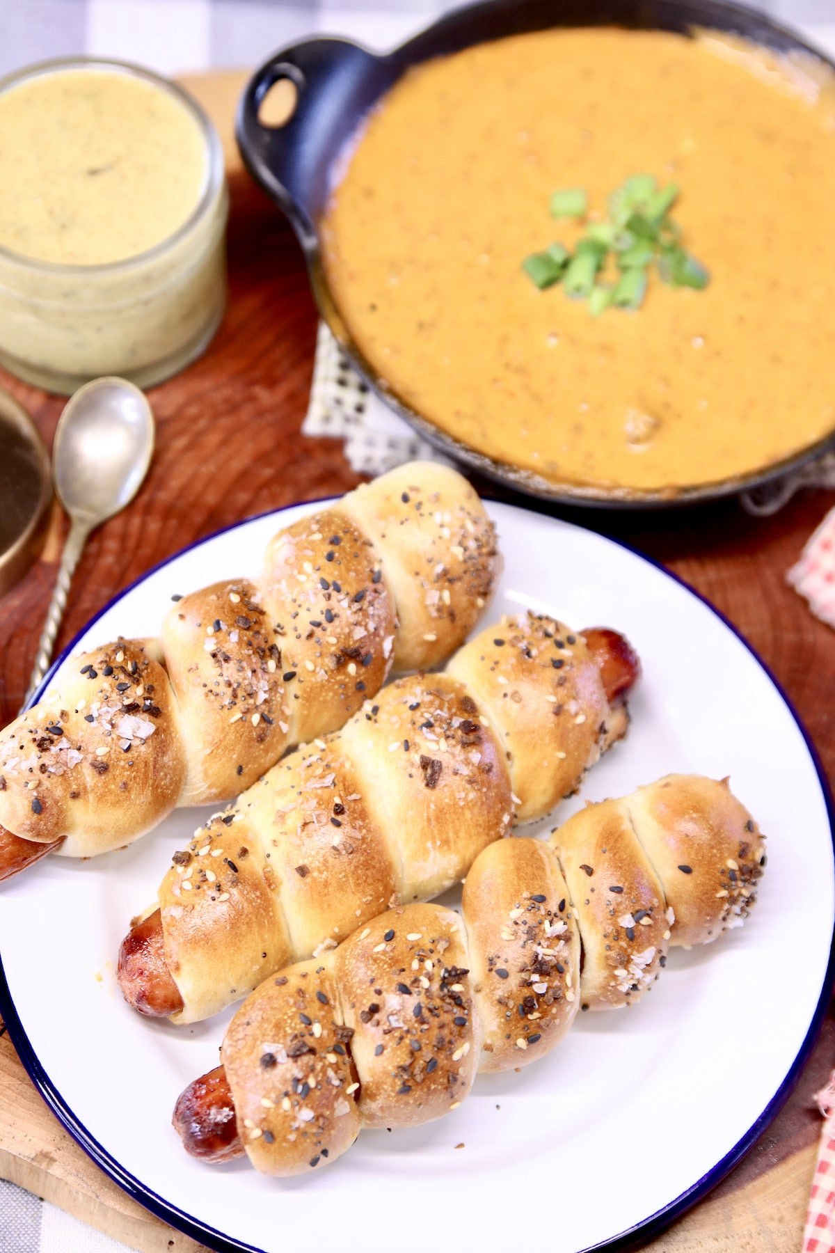 plate of 3 pretzel dogs, cheese dip in background