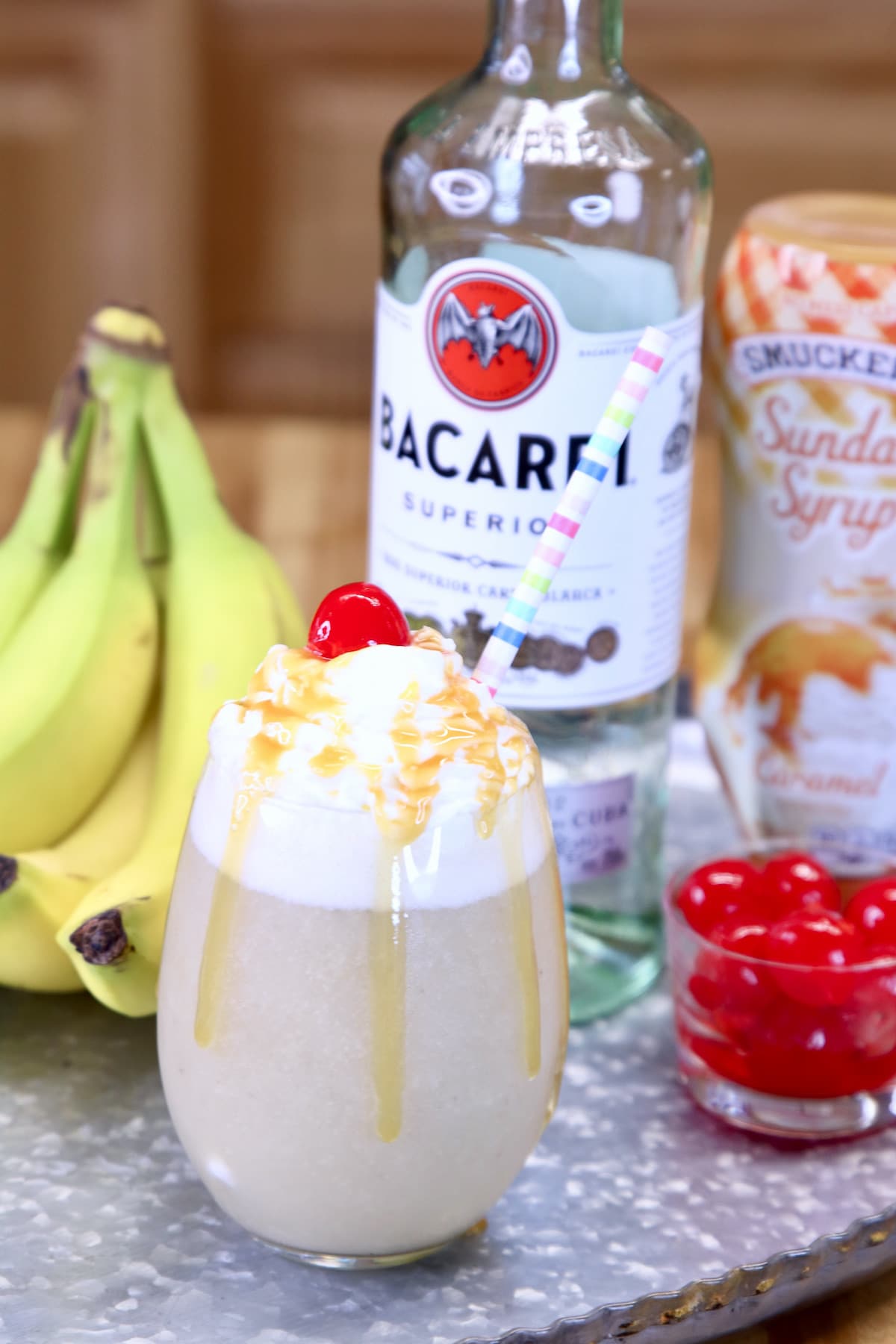Banana Daiquiri on a tray with bananas, Bacardi rum, bowl of cherries.