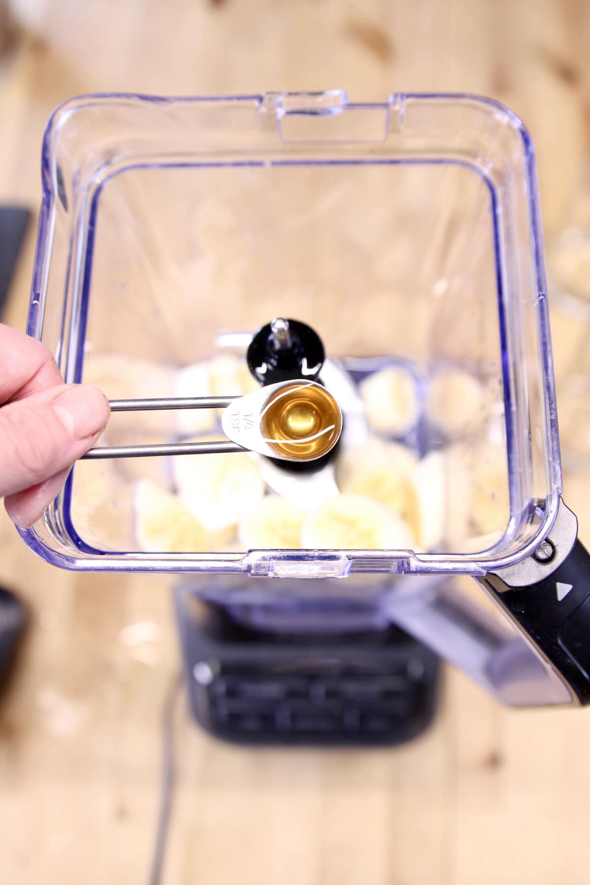 spoon of vanilla extract over a blender.