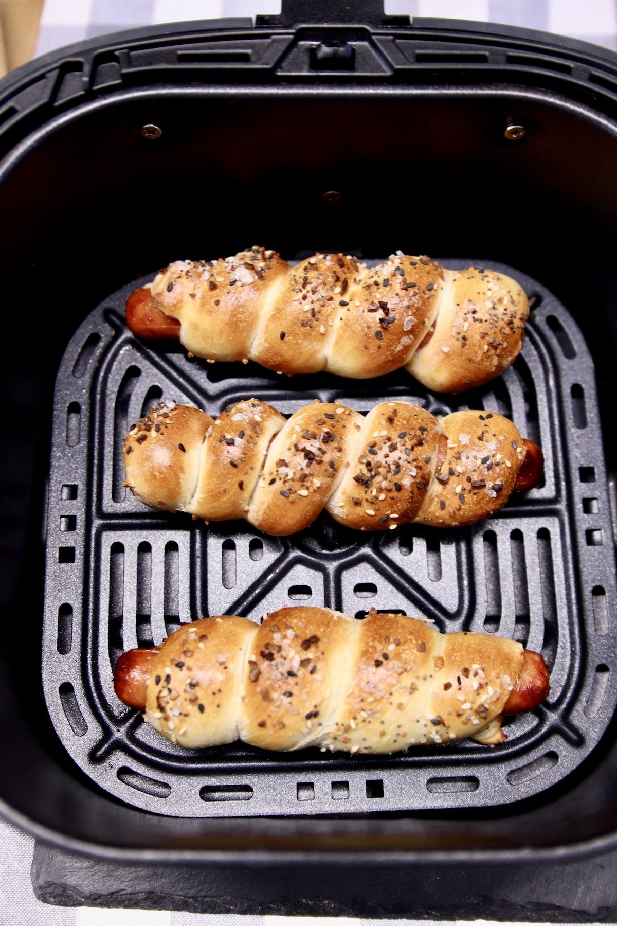 3 pretzel dogs in an air fryer - golden brown.