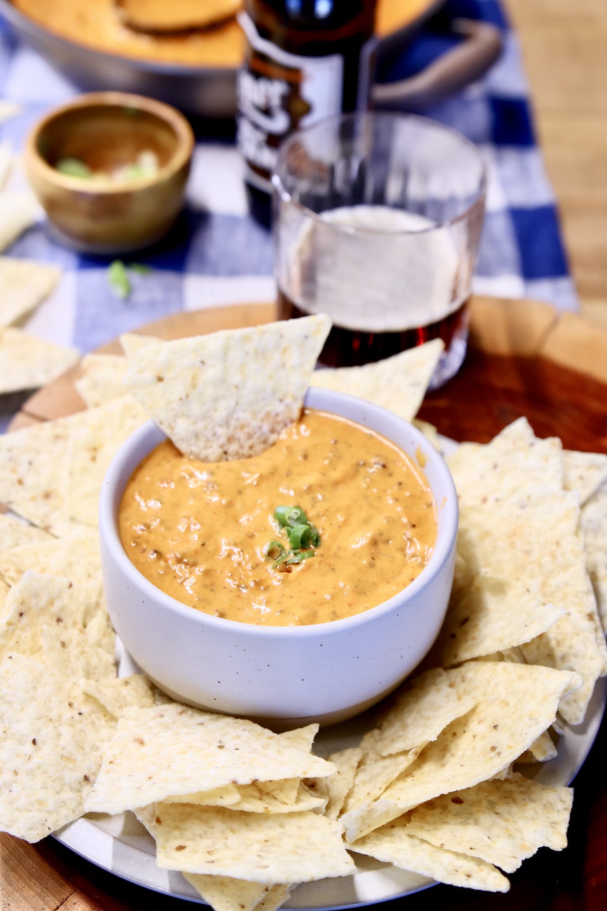 Platter of tortilla chips with chili cheese dip in a bowl in the center.