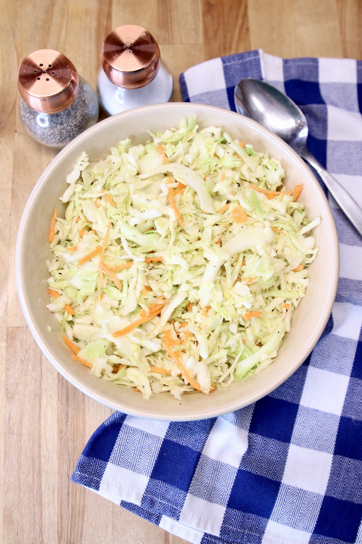 Overhead of coleslaw on a blue check napkin.