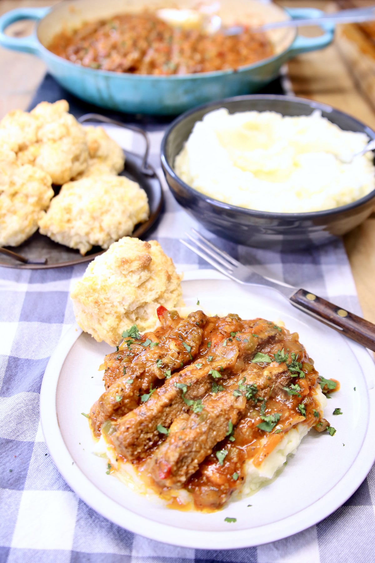 Swiss steak on a plate over mashed potatoes. 