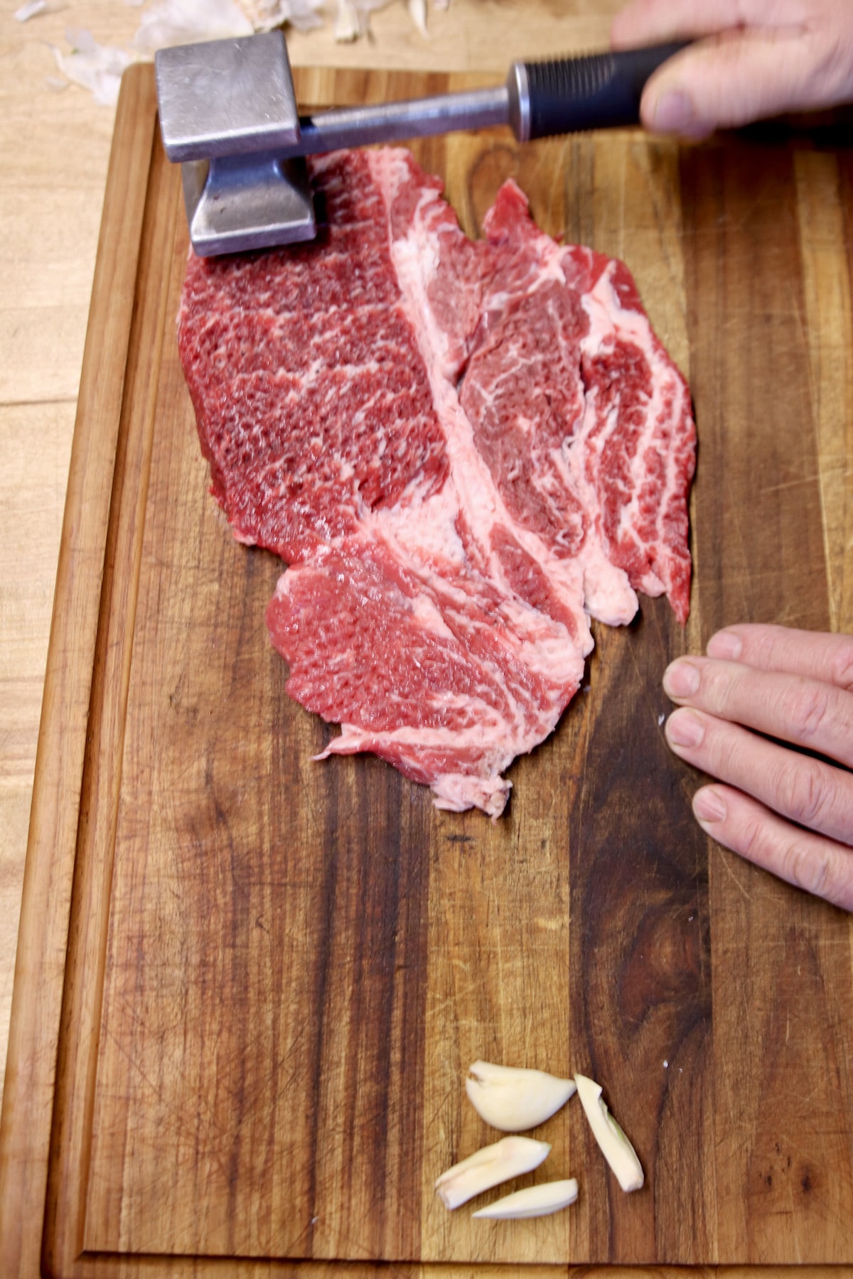 pounding a chuck steak with a meat mallet