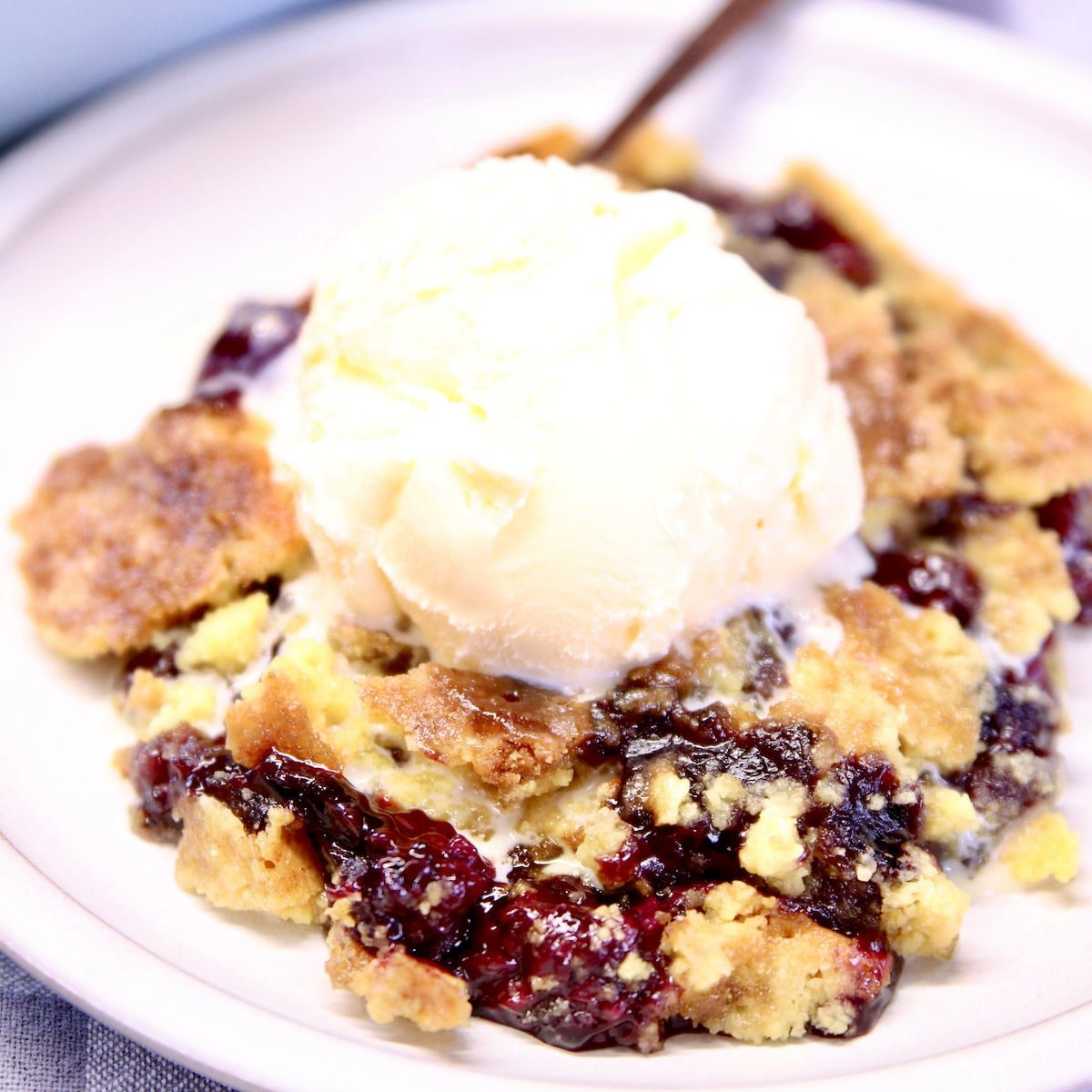 blackberry dump cake with ice cream on a plate.