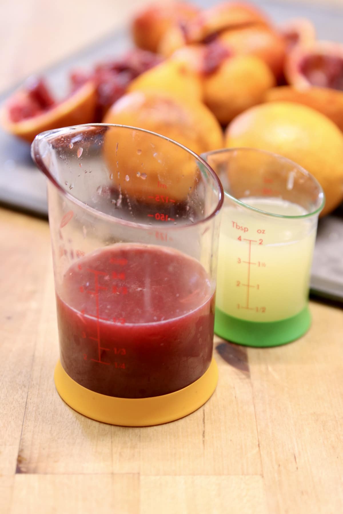 Measuring cups with blood orange juice and lime juice.