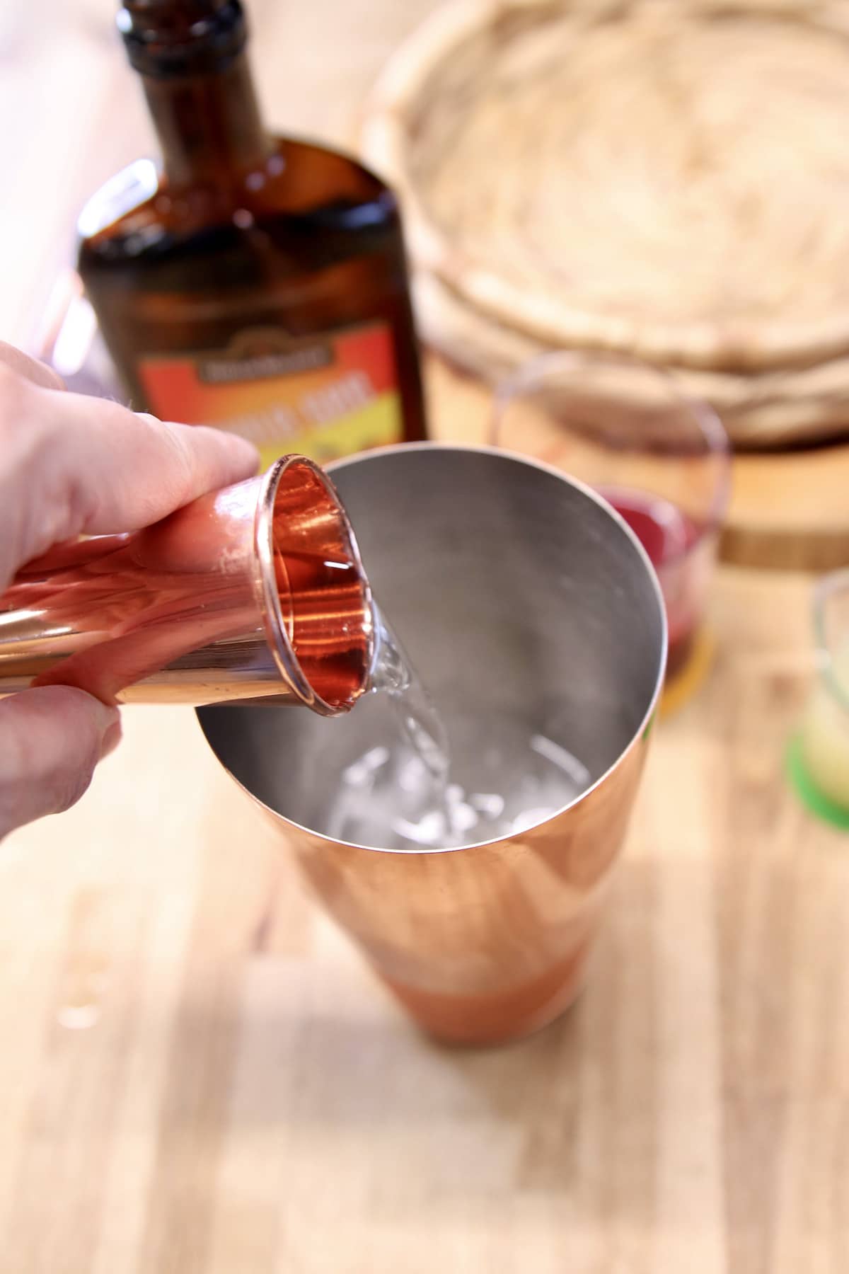 pouring triple sec into a cocktail shaker.