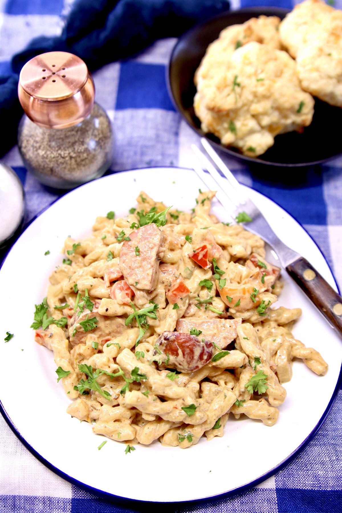 overhead of plated Cajun Sausage Pasta with plate of biscuits.