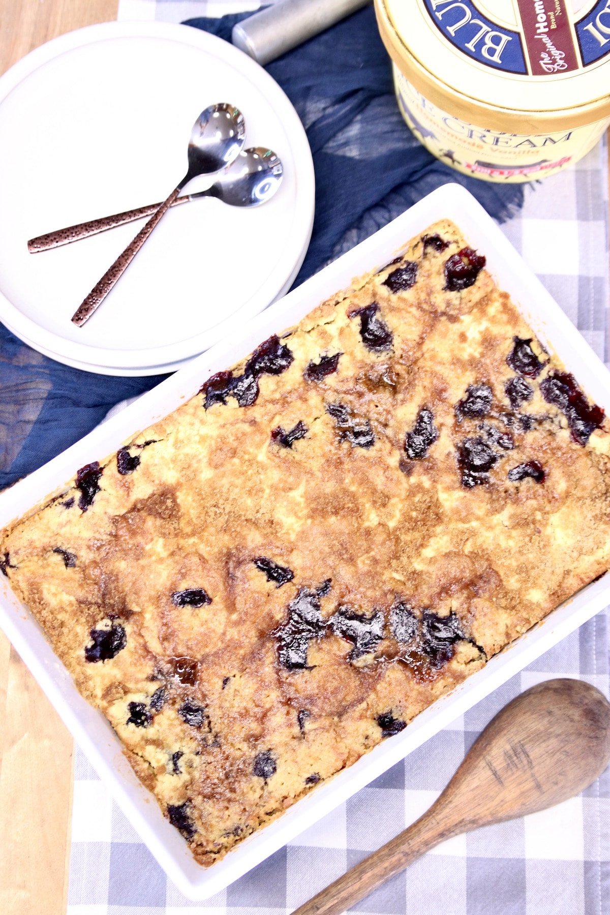 Blackberry Dump Cake in a pan, plates with spoons, ice cream.