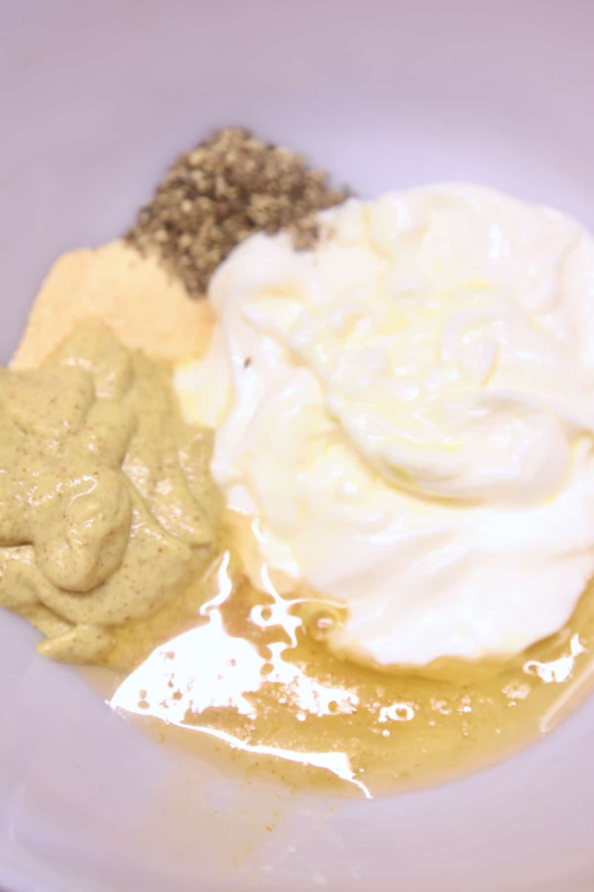 Bowl with mayonnaise, mustard, honey, seasonings.