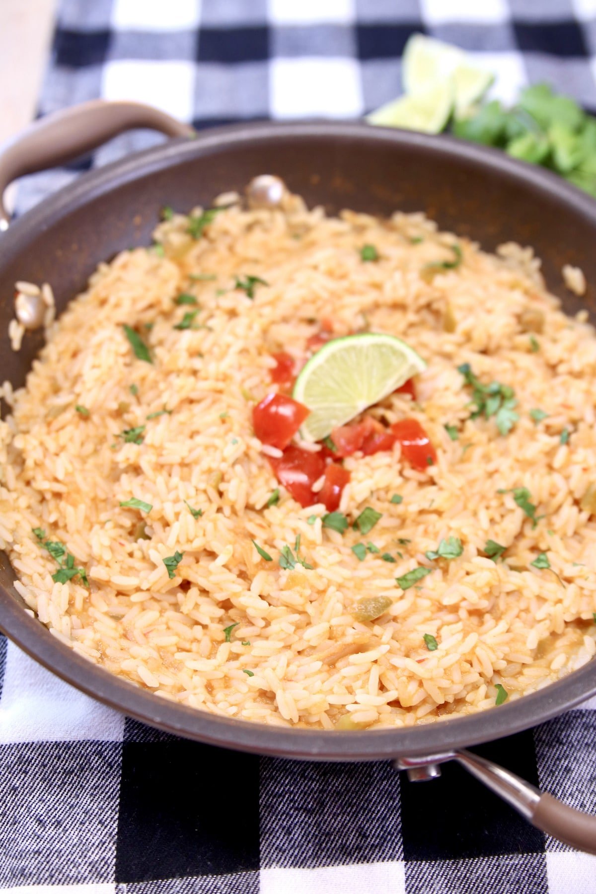 Pan of Spanish rice with cilantro, tomato garnish.