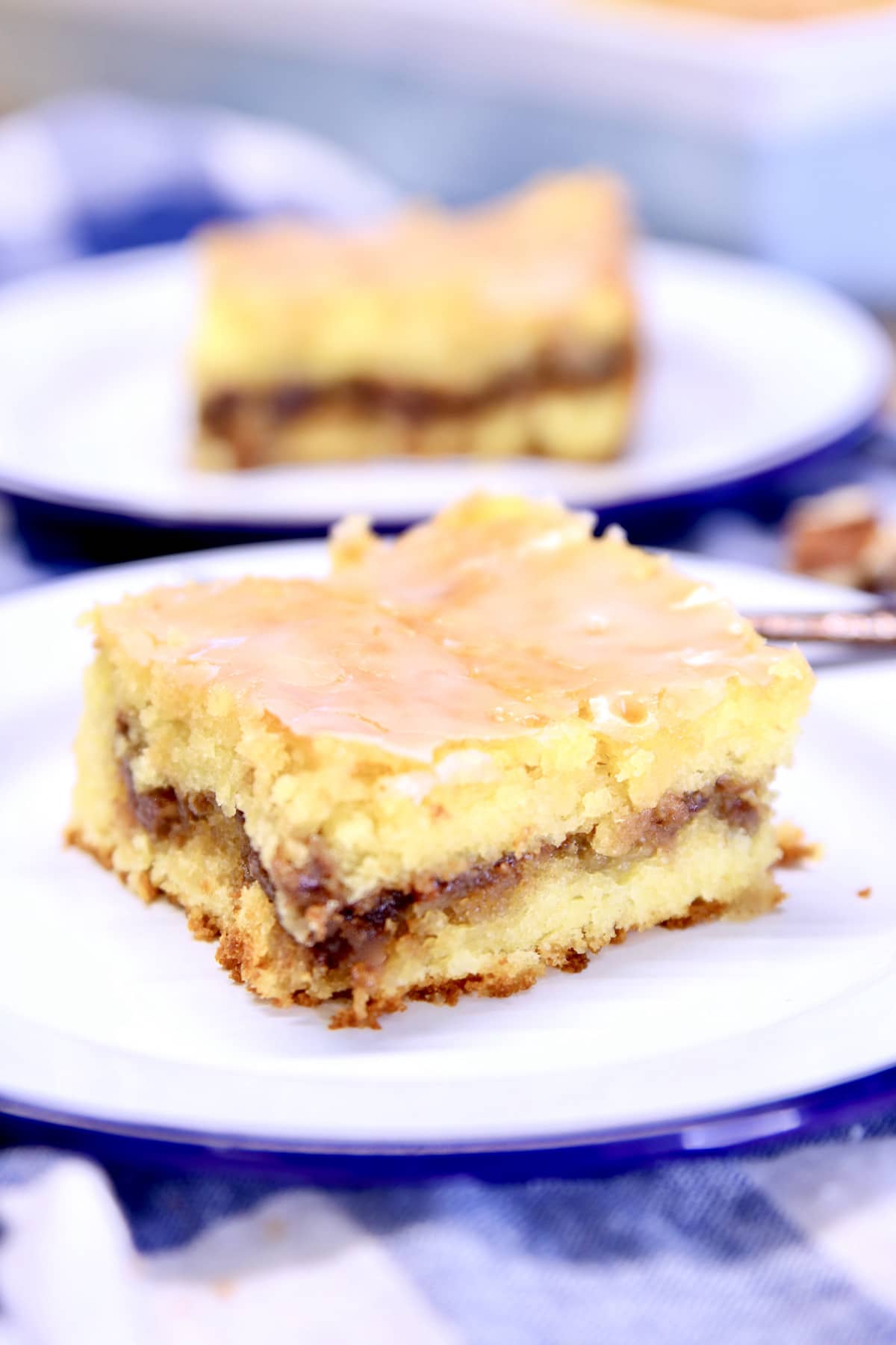 Honey Bun Cake is a classic dessert that is simple to make for any day of the week and delicious enough for special occasions. A cake mix recipe with a cinnamon and pecan filling, topped with a sweet powdered sugar icing. Honey Bun Cake slice on plate.