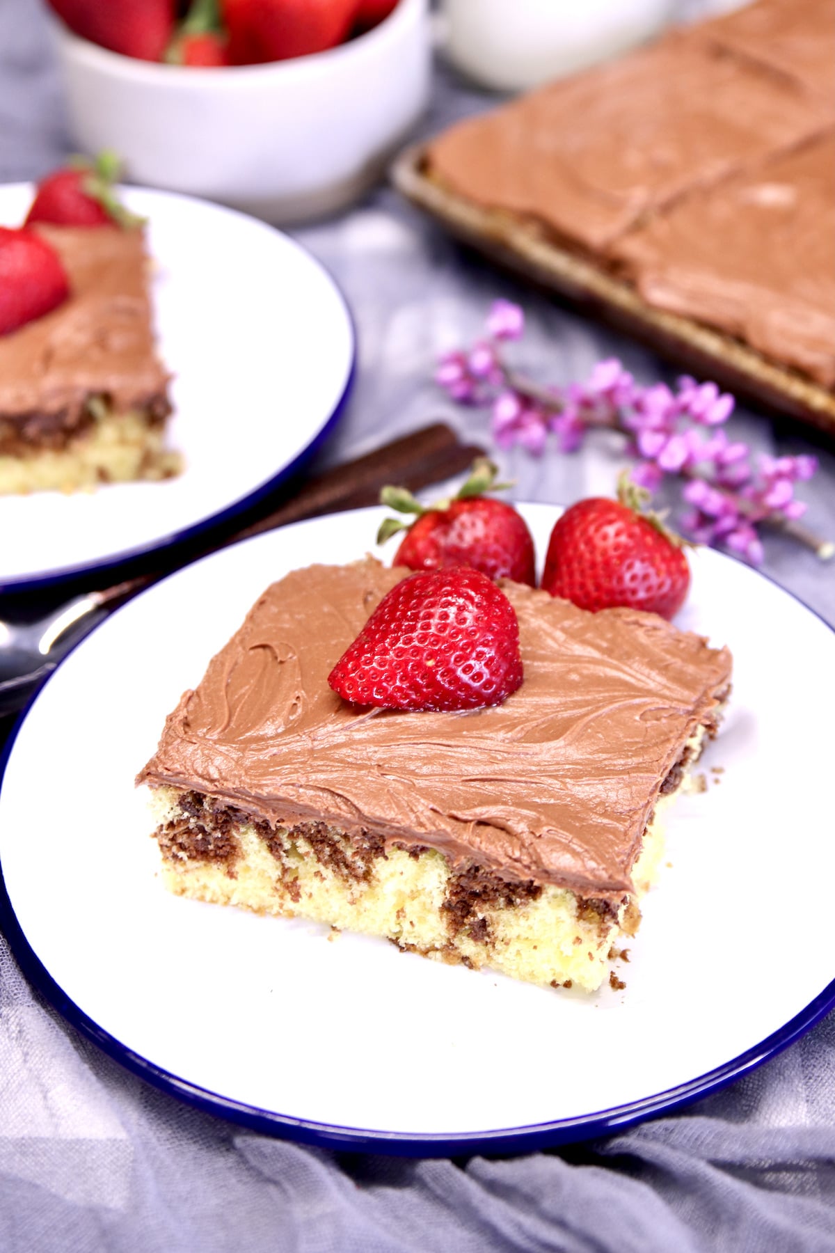 slice of sheet cake with chocolate icing. Strawberry garnish.