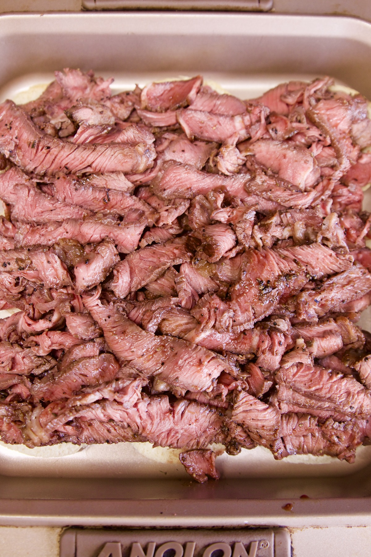 pan of slider buns with thin sliced steak.
