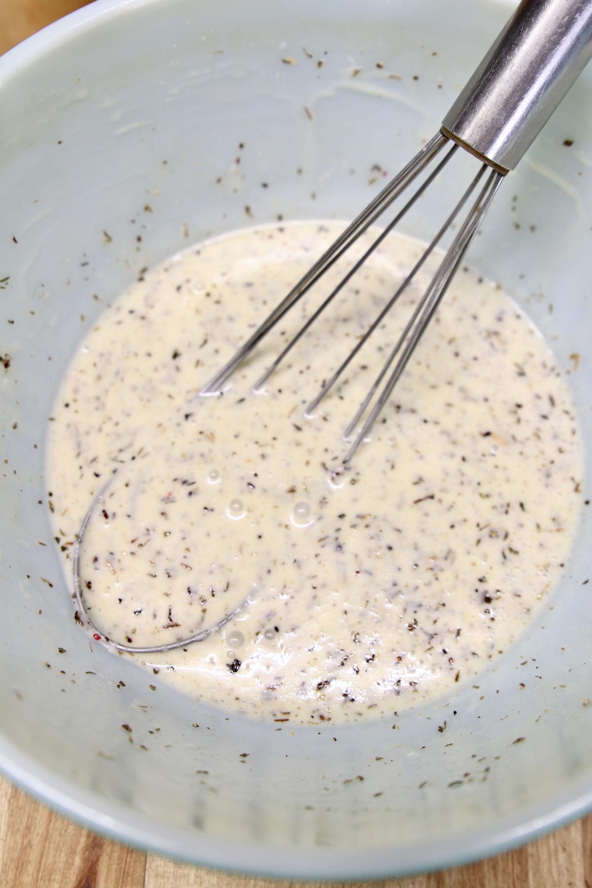 bowl with whisk in creamy Italian salad dressing.