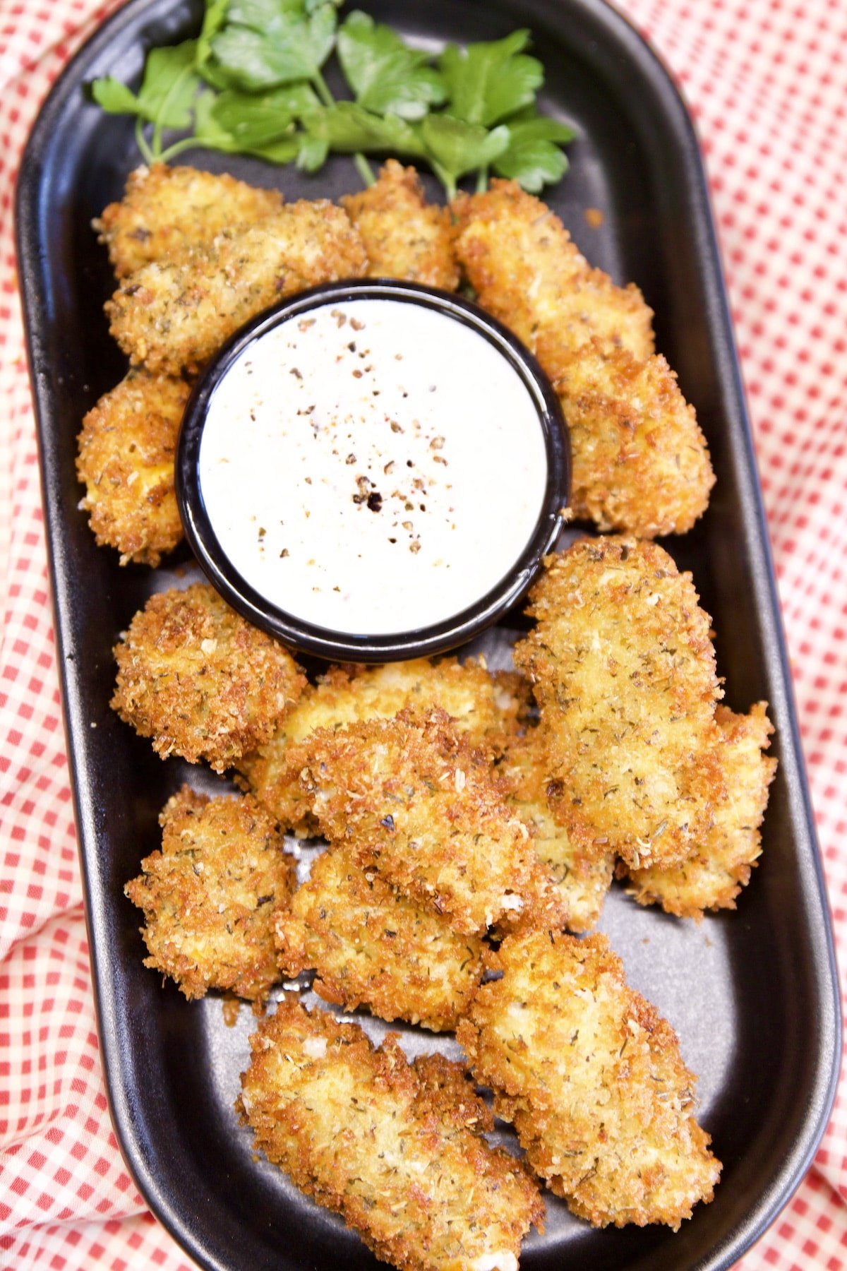 Oval tray of fried cheese curds with ranch dip in a bowl.