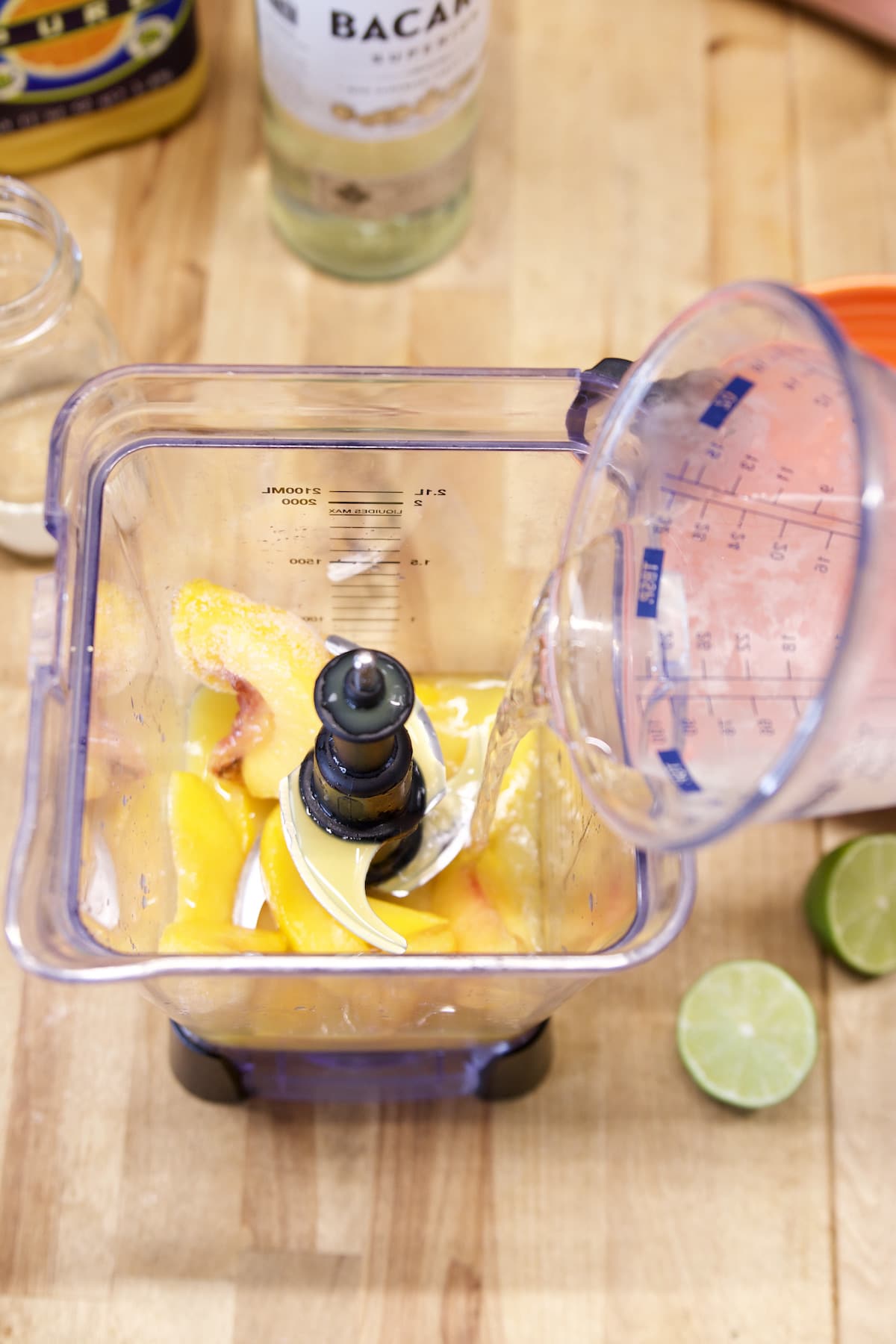 pouring rum into a blender with peaches.