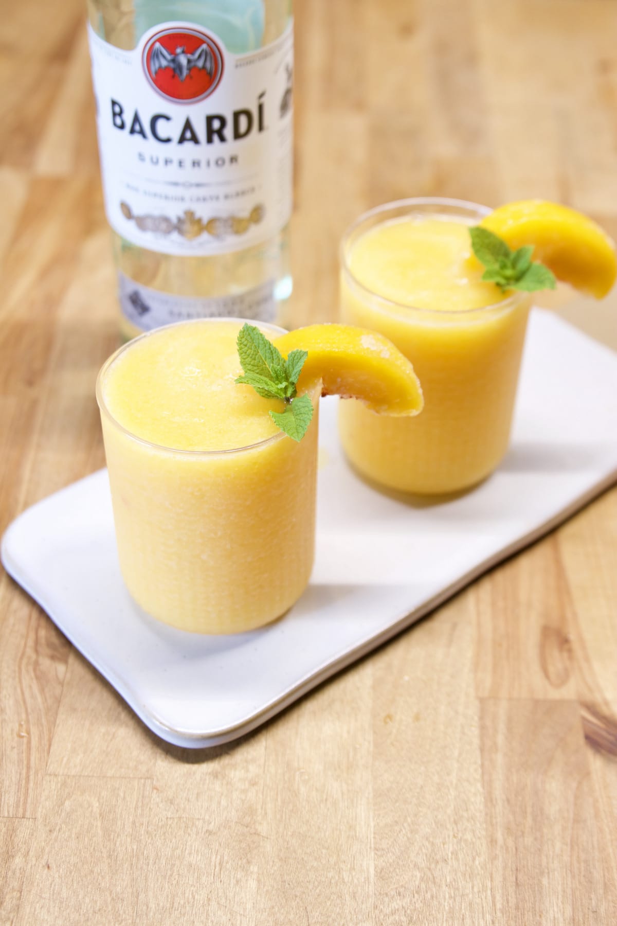 Rum bottle with 2 peach daiquiris.