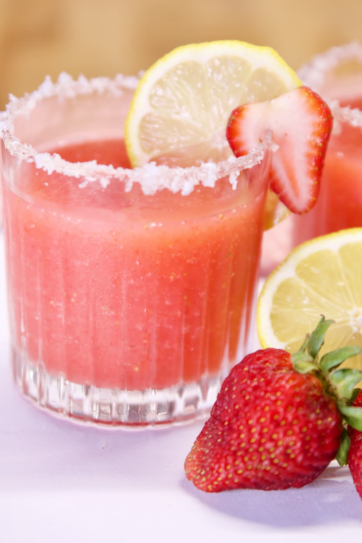 Strawberry Margarita in an old fashioned glass. Lemon and strawberry garnish.