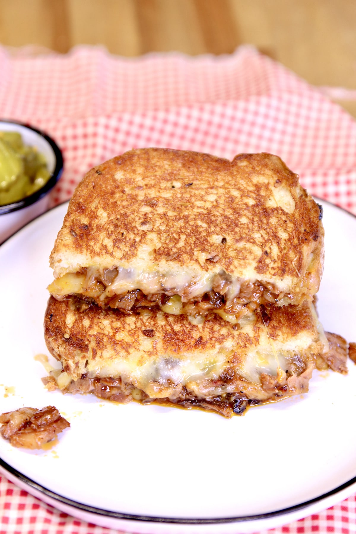 Brisket grilled cheese sandwich on a plate, cut in half.