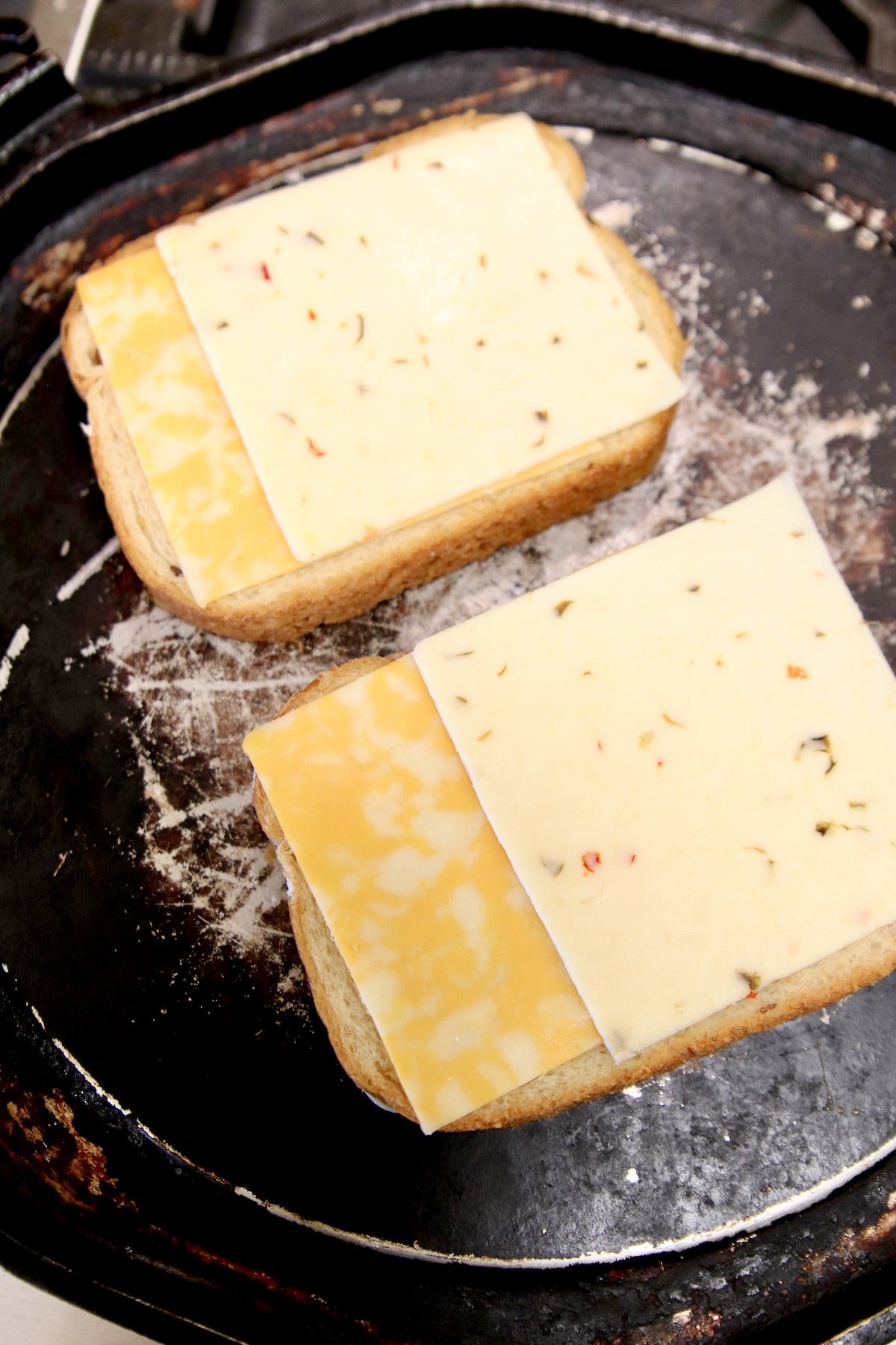 Griddle with 2 pieces of bread with cheese slices.